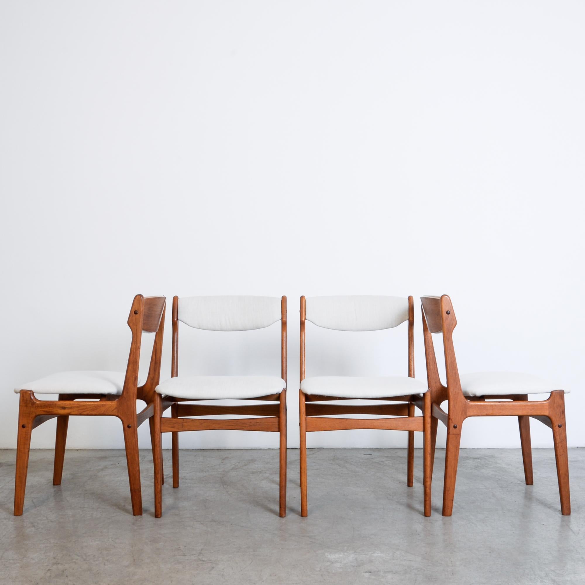 From France, circa 1960, a set of four upholstered dining chairs in teak. Influenced by the contemporary fashion of Modern design, these chairs are composed by simplified geometric forms, with organic variations reflecting the distinctive contours
