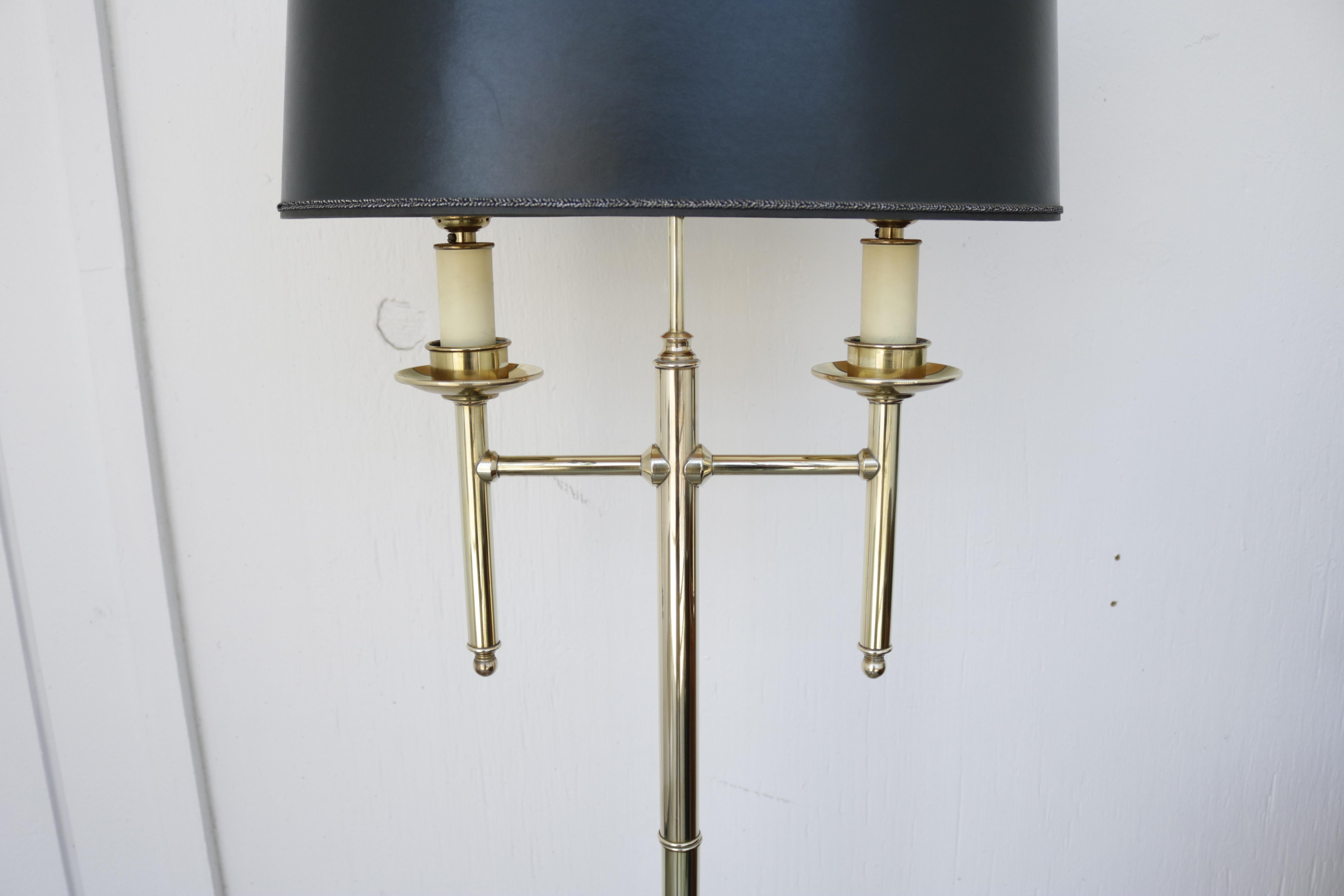 French floor lamp in brass with black ellipse shaped paper shade. Finial has a brass ring design on top. Two sockets.