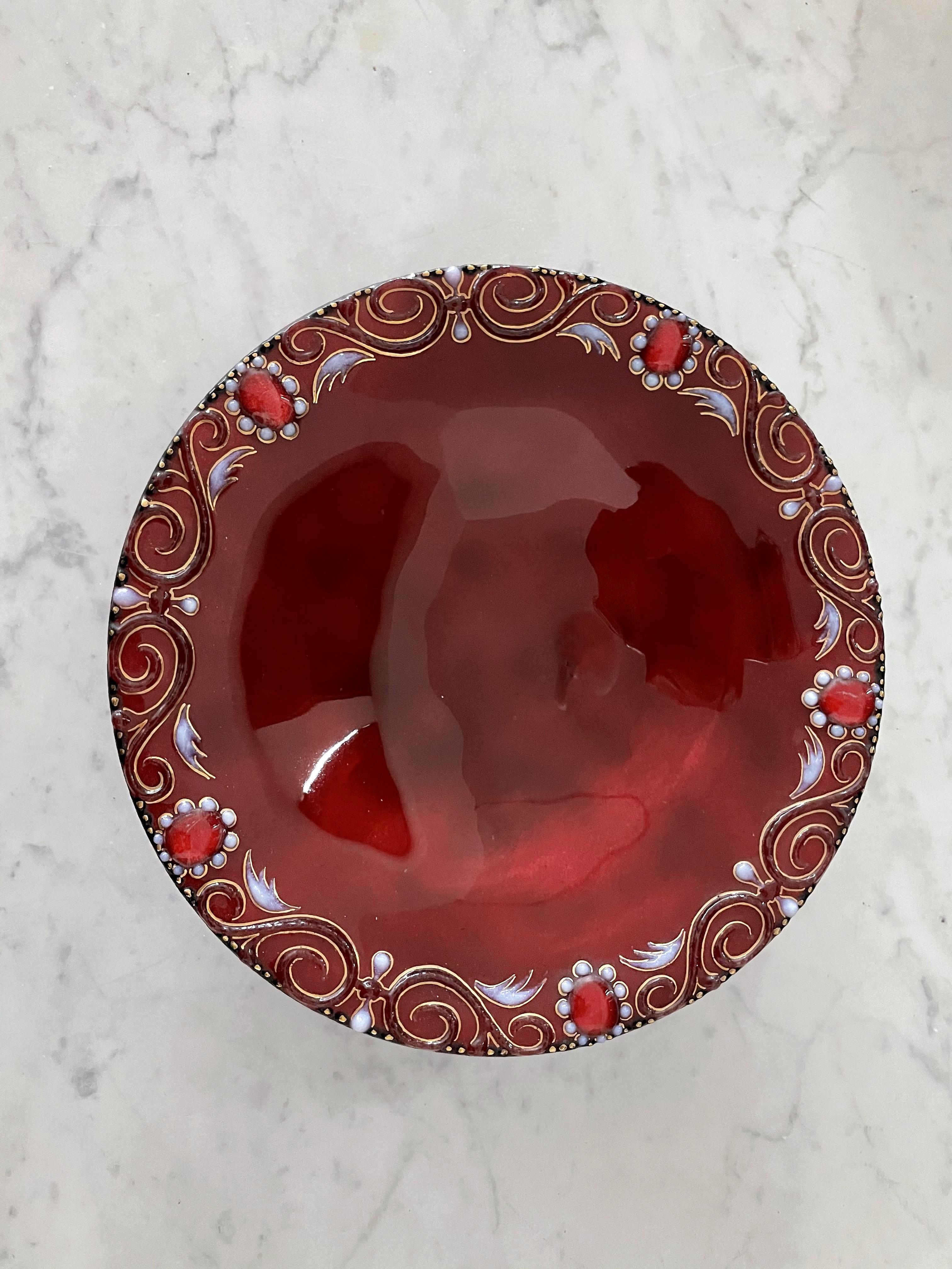 A mid-20th-century French Limoges enamel (the richest surviving corpus of medieval metalwork) centerpiece or decorative dish, signed Atelier Tochard Bonhomme in a burgundy red color with handpainted wing-like, flower and s-scroll details around.