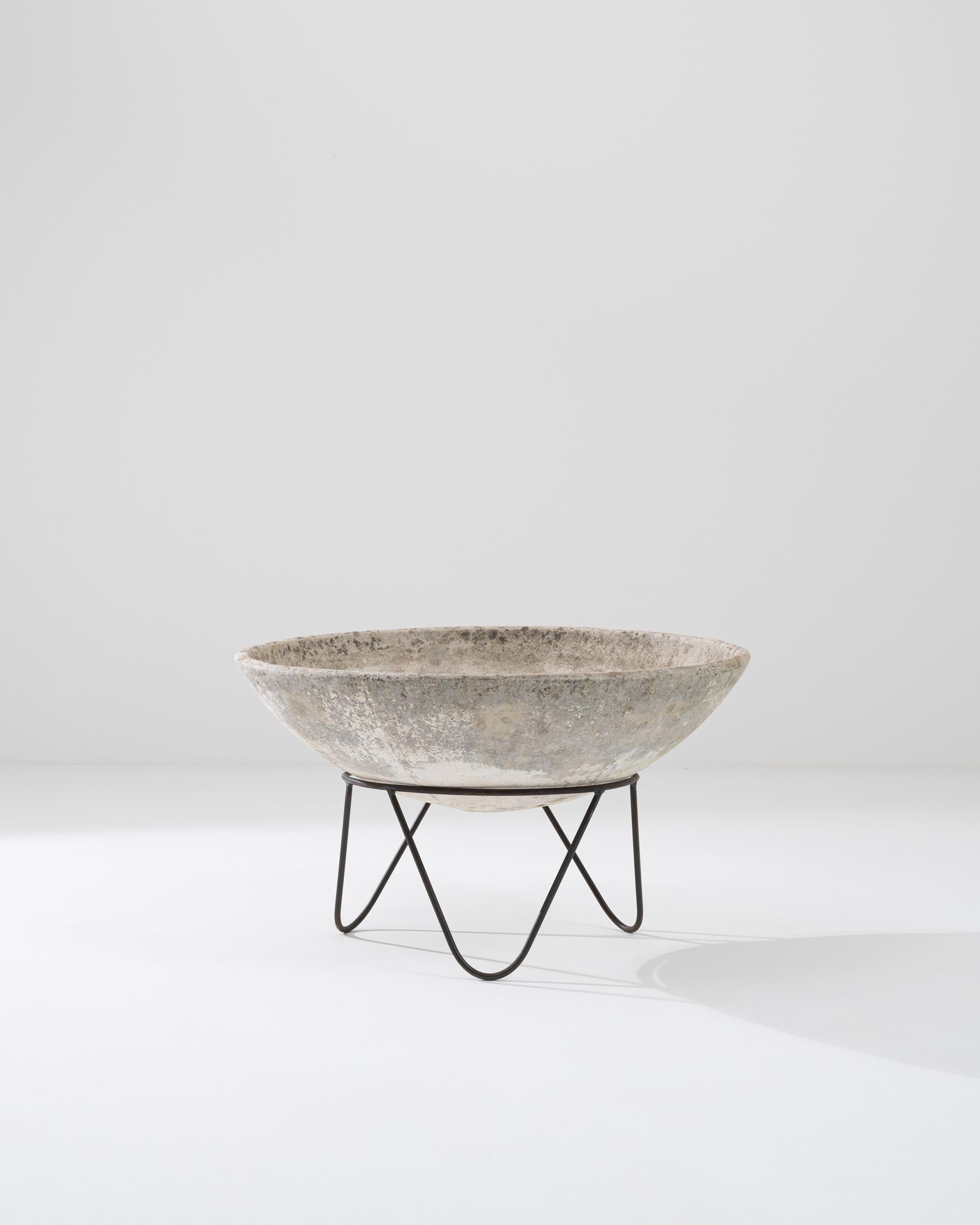 A concrete planter on a metal stand from France, circa 1960. This piece consists of a deep concrete bowl, which has developed a rich patina, over top a tripod of welded hairpin legs. Waiting to be filled with numerous possibilities, this unique