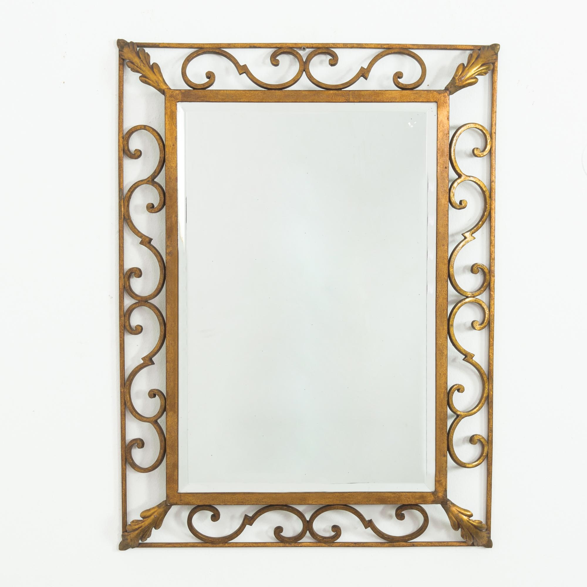 Ajoutez une touche d'élégance vintage à votre intérieur avec ce miroir en métal français des années 1960. Cette pièce étonnante présente un cadre en fer forgé magnifiquement travaillé avec des volutes complexes, finies dans un ton doré chaud et