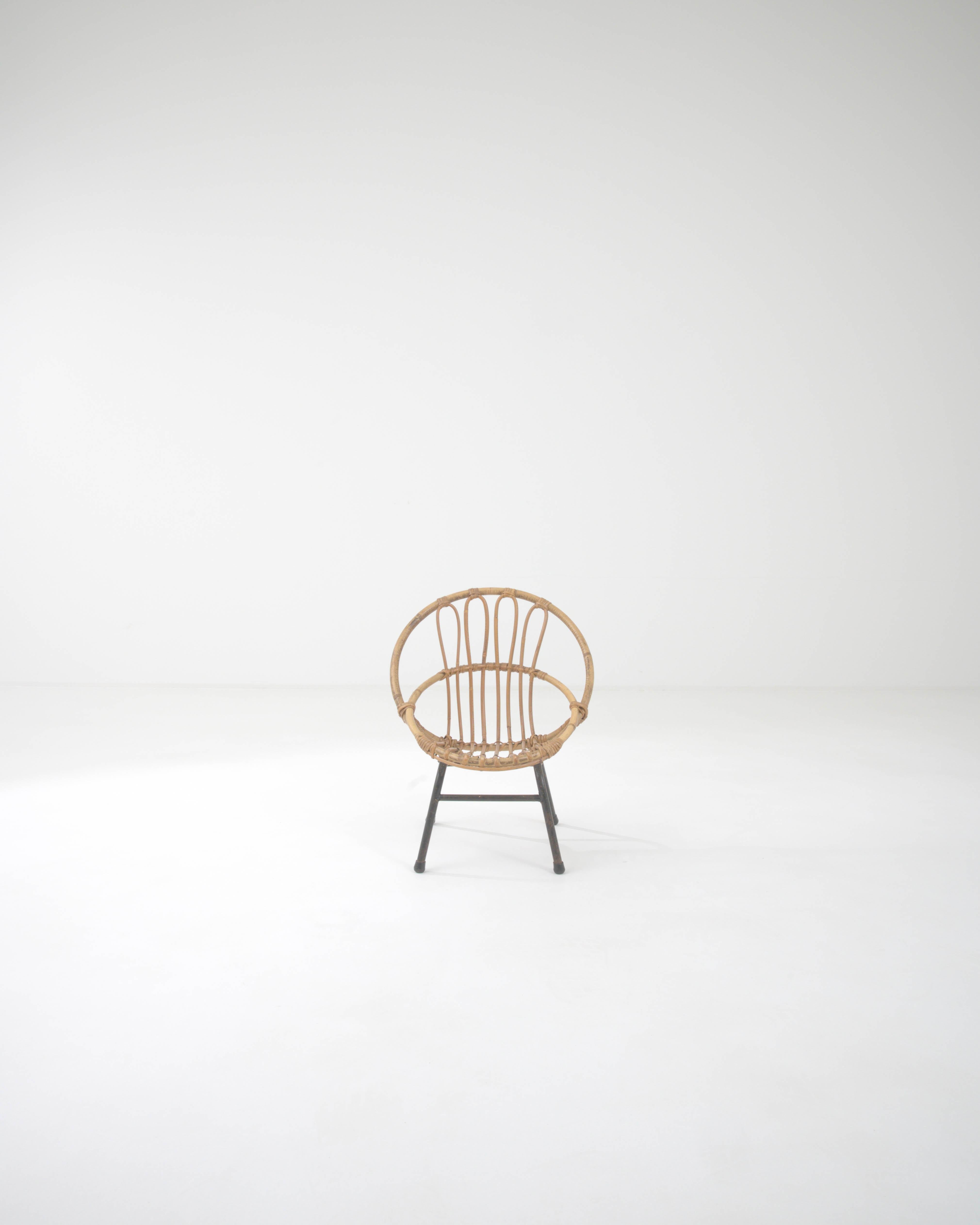 A child's chair from France, circa 1960. This french-made miniature armchair is a playful twist on a midcentury classic. Using lashed together rattan, artisans have crafted a chair both geometrically pleasing and surprisingly comfortable. Created by