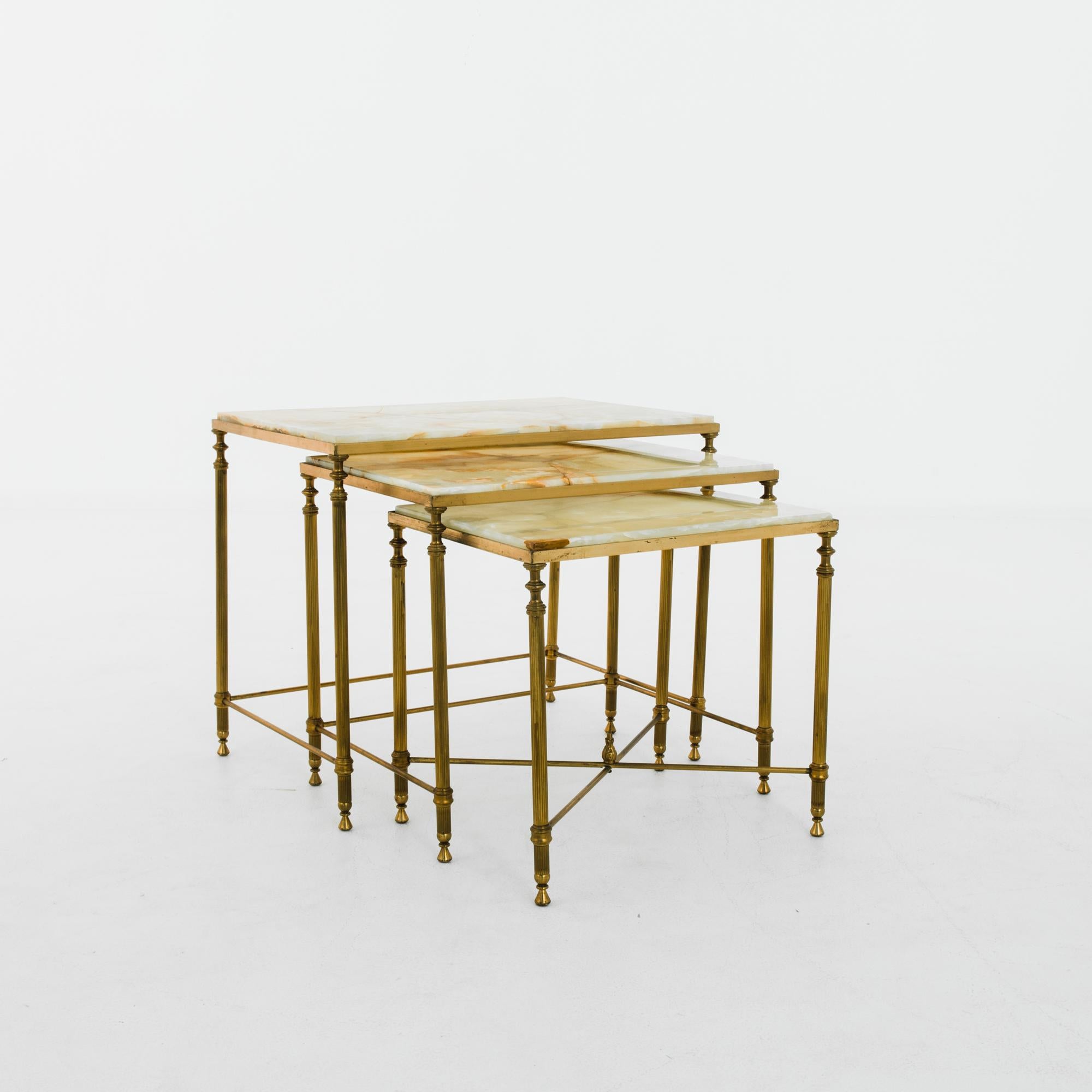 A set of three nesting tables from 1960s France. A brass frame supports a square tabletop of faceted marble; the deep amber veining of the polished stone brings out deep gilded tone of the metal. The frame is light, yet with an elegant profile. The