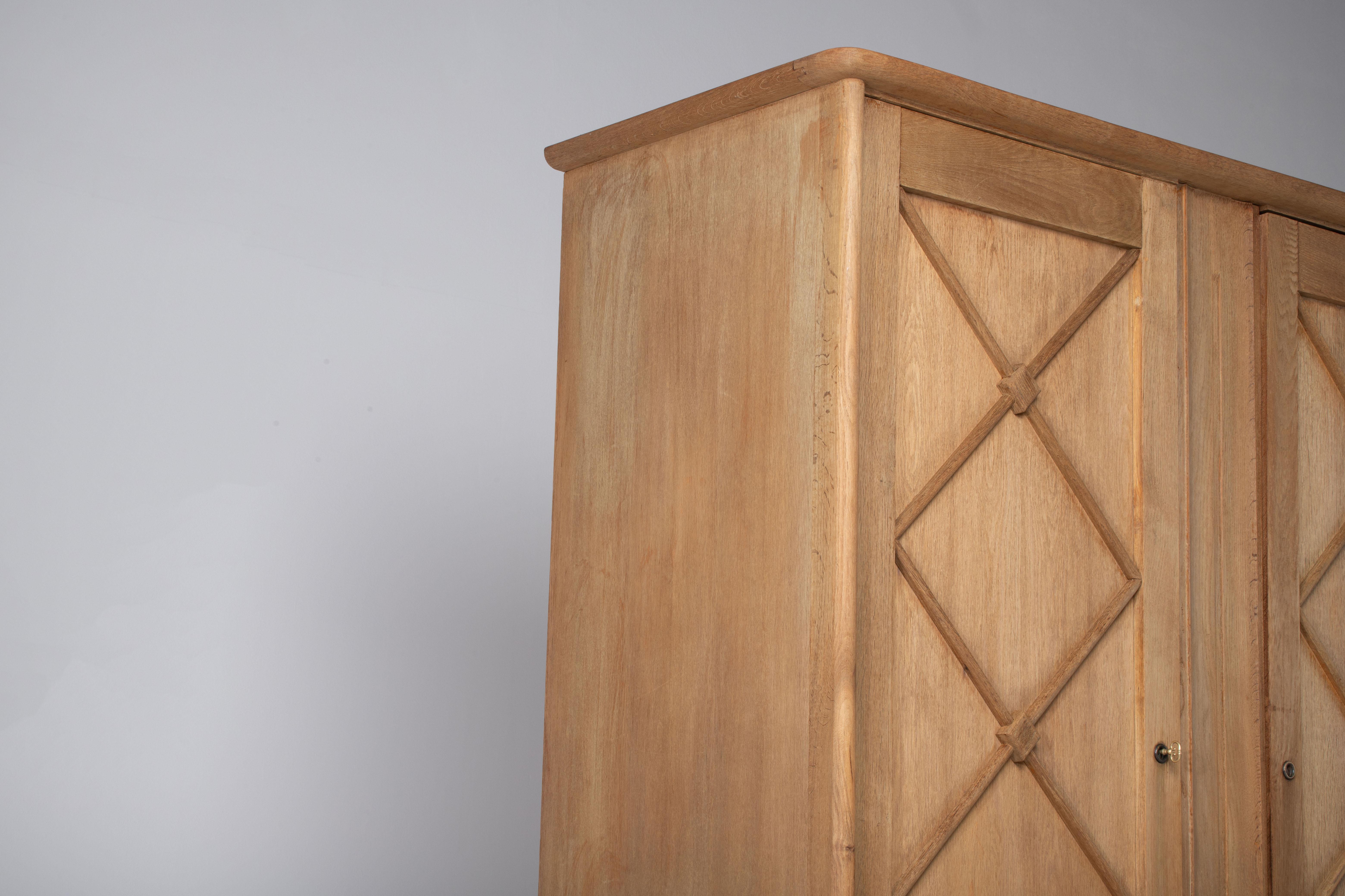 Beautiful oak vintage wardrobe made in the 1960s reminiscent of the work of Jean Royere. It has a double opening doors to hanging space with geometrical patterned doors. A great vintage piece in good condition which would bring a huge touch of style