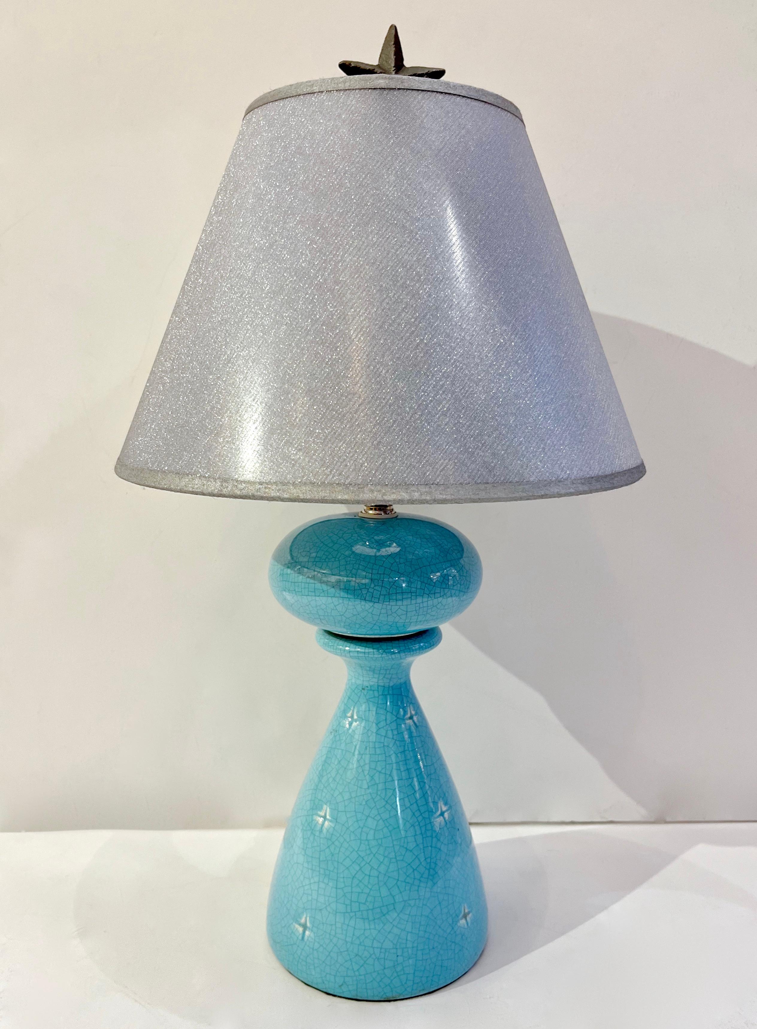 A delightful vintage pair of French ceramic table lamps with Art Deco flair worked with the craquele technique and decorated with indented stars in the bodies. The color in sky blue aquamarine adds to the desirability of these cute lamps, their size