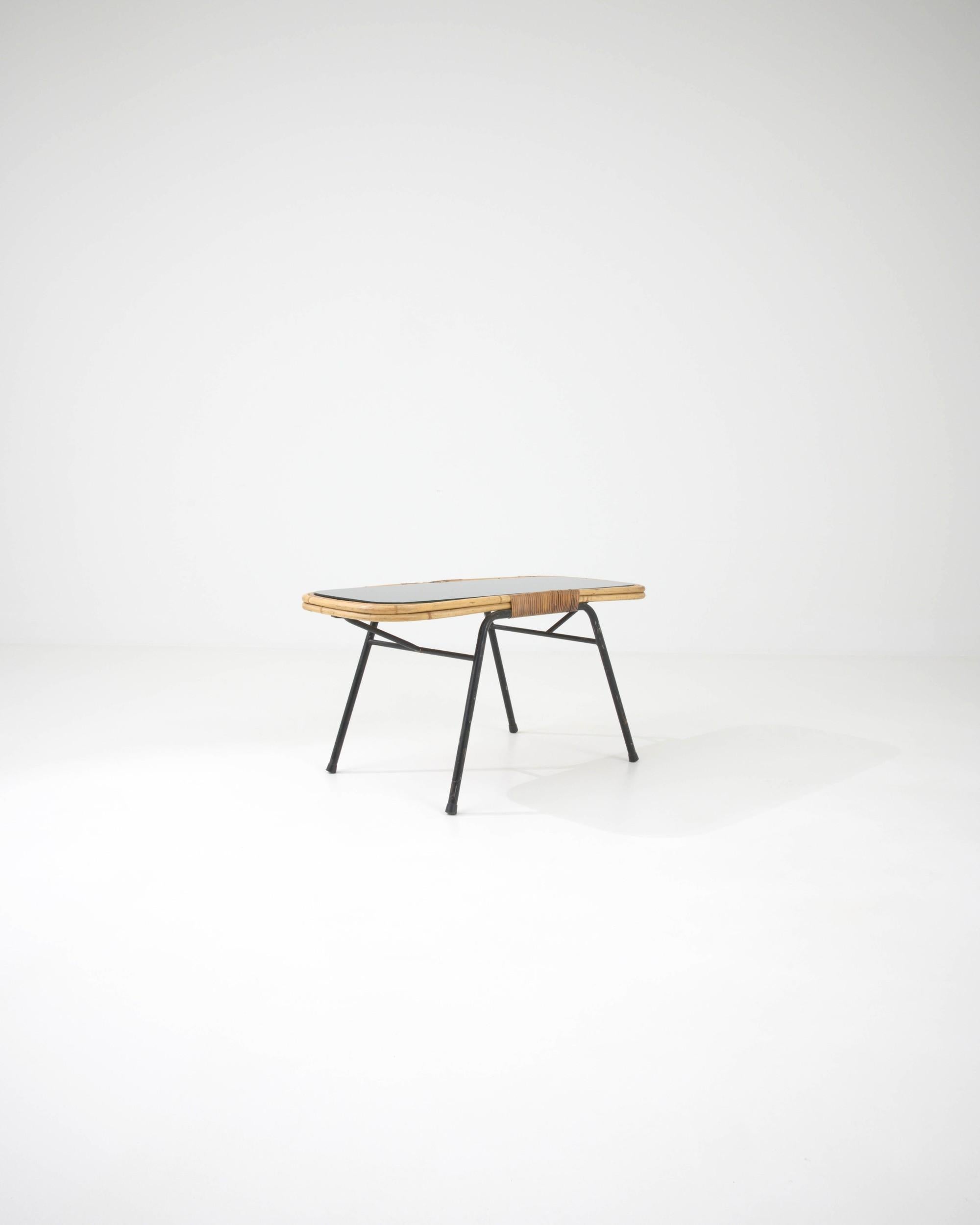 Cette table basse au design charmant du milieu du siècle a été fabriquée en France, vers 1960.  Créée en pliant des tiges de rotin en courbes et en arcs, cette petite table invite à réfléchir à sa délicieuse construction. Le rotin constitue un