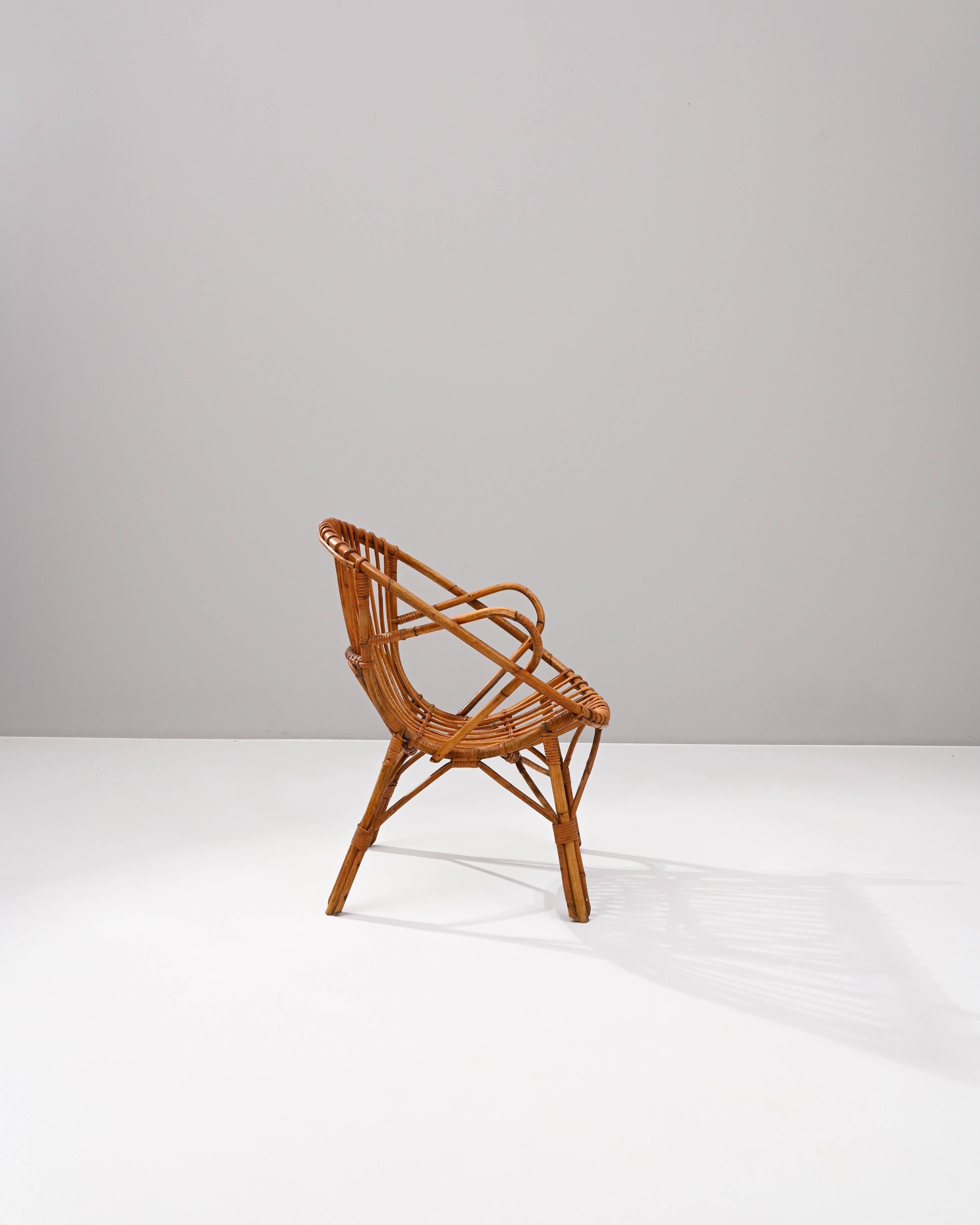 A wooden armchair from France, circa 1960. This French-made armchair is a playful twist on a midcentury classic. Using lashed together rattan, artisans have crafted a chair both geometrically pleasing and surprisingly comfortable. Created by looping