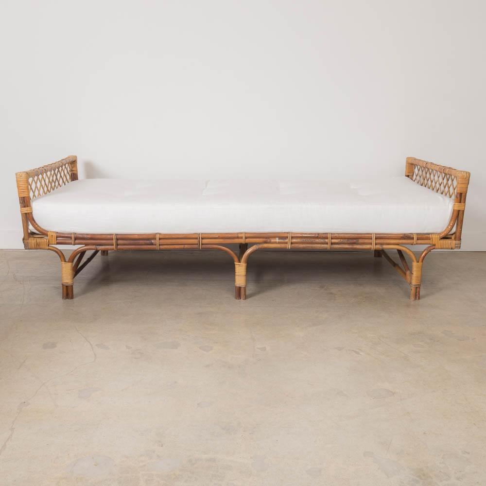 Incredible vintage rattan daybed from France, 1960s. Long rattan frame with croisillon detail. Original rattan shows nice age and patina. Newly added cream linen cushion with button detail. Beautiful statement piece. 