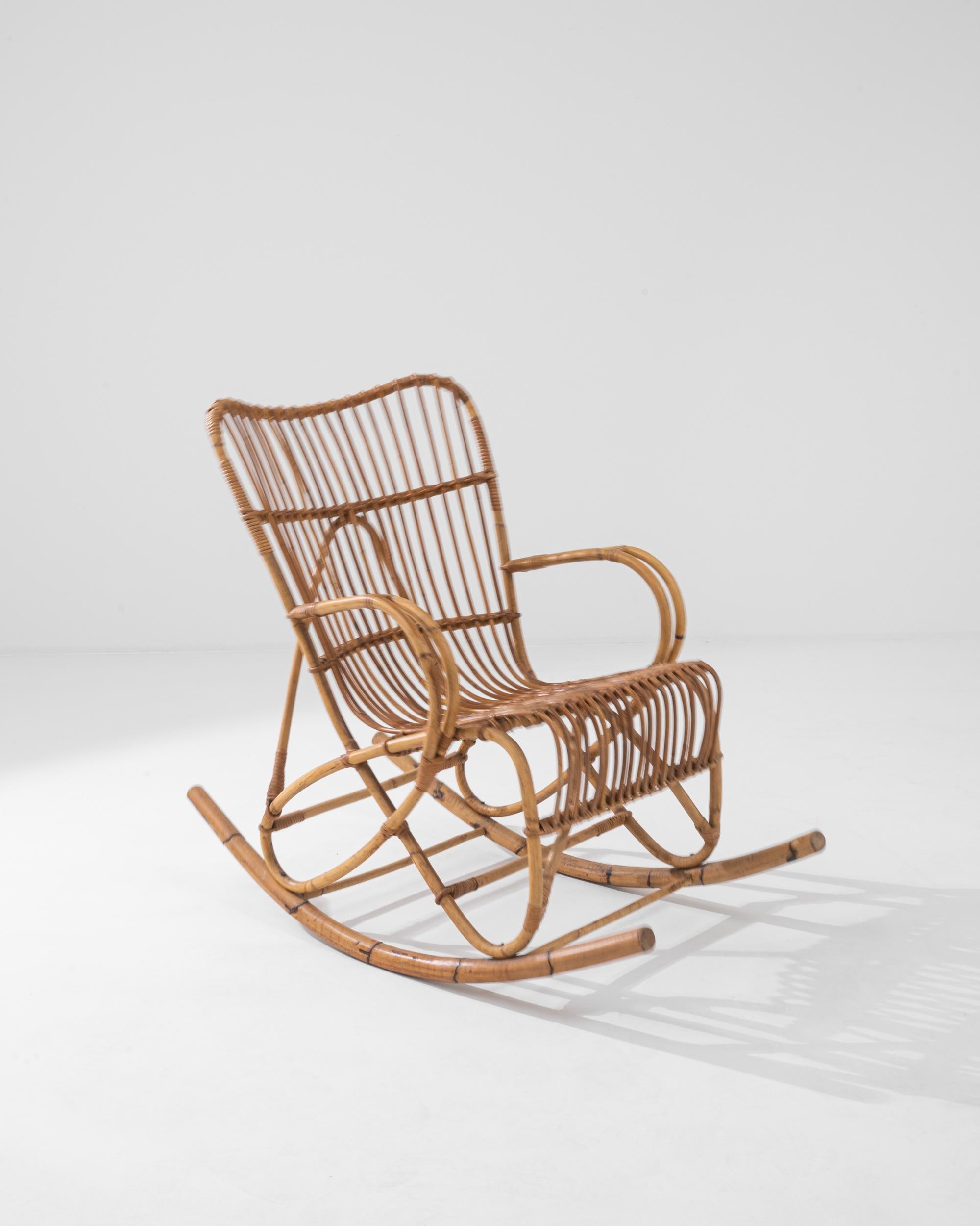 A wooden armchair from France, circa 1960. This French-made armchair is a playful twist on a classic rocker. Using lashed together rattan, artisans have crafted a chair both geometrically pleasing and surprisingly comfortable. Created by looping
