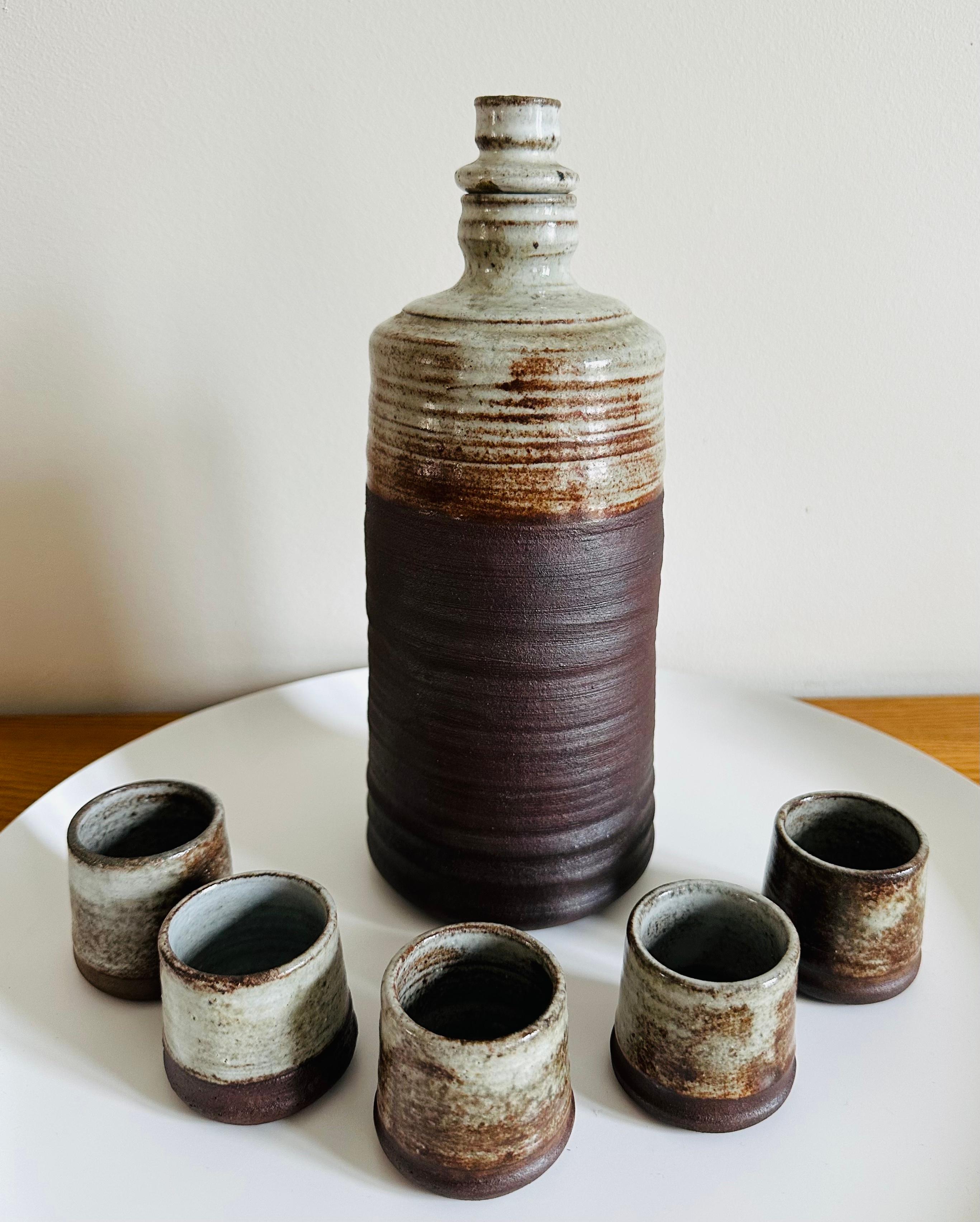 An absolutely wonderful 1970s French Studio Pottery bottle with its original stopper and five matching cups. The set may have been designed as a Japanese Sake Set. The base is incised with MM and despite a great deal of research I've been unable to
