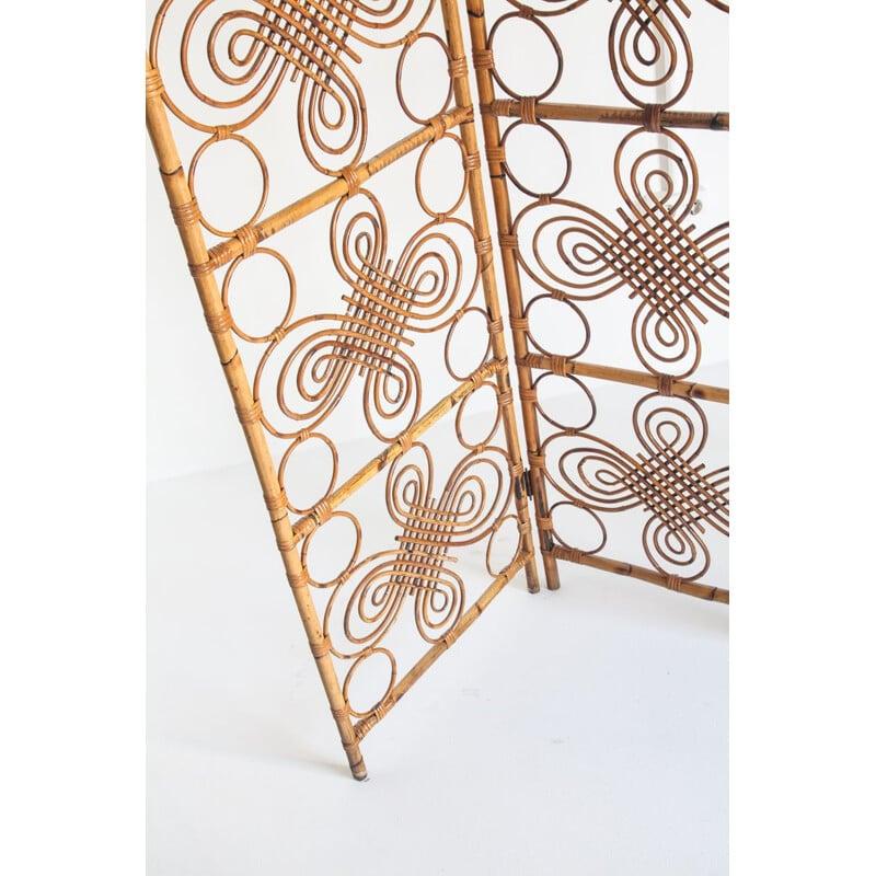 Questo divisorio in bambù finemente lavorato è un'opera d'arte che racconta una storia di creatività e artigianato. Le intricate volute che attraversano la sua superficie si intrecciano con delicati cerchi che creano un arazzo visivo ipnotico. Ogni
