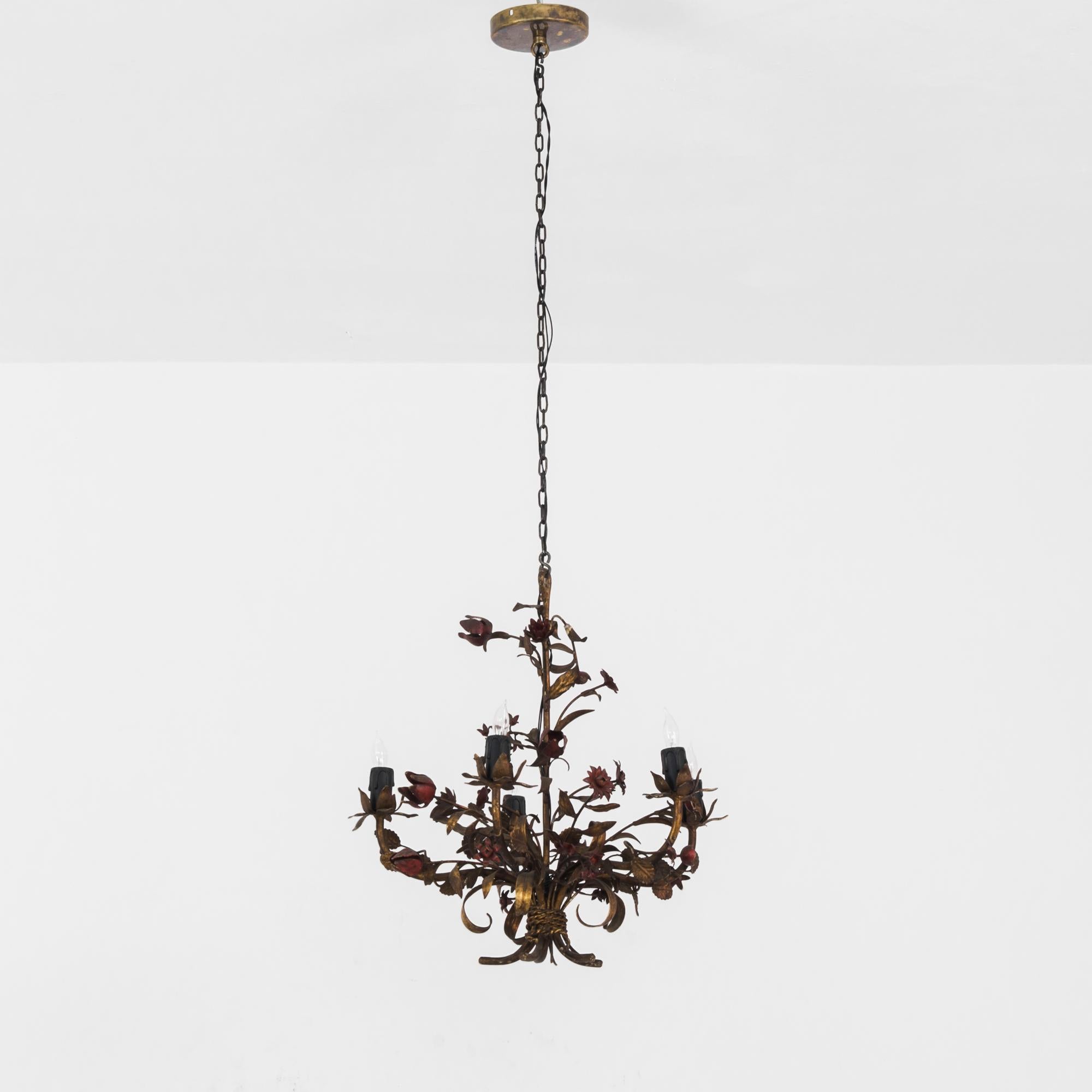 A metal chandelier from 1960s France. Unruly and romantic. Lifelike metal flowers and leaves — roses, daisies and anemones — tangle around four upraised arms bearing candle bulbs. The sconces are embellished with petals and sepals, framing the light