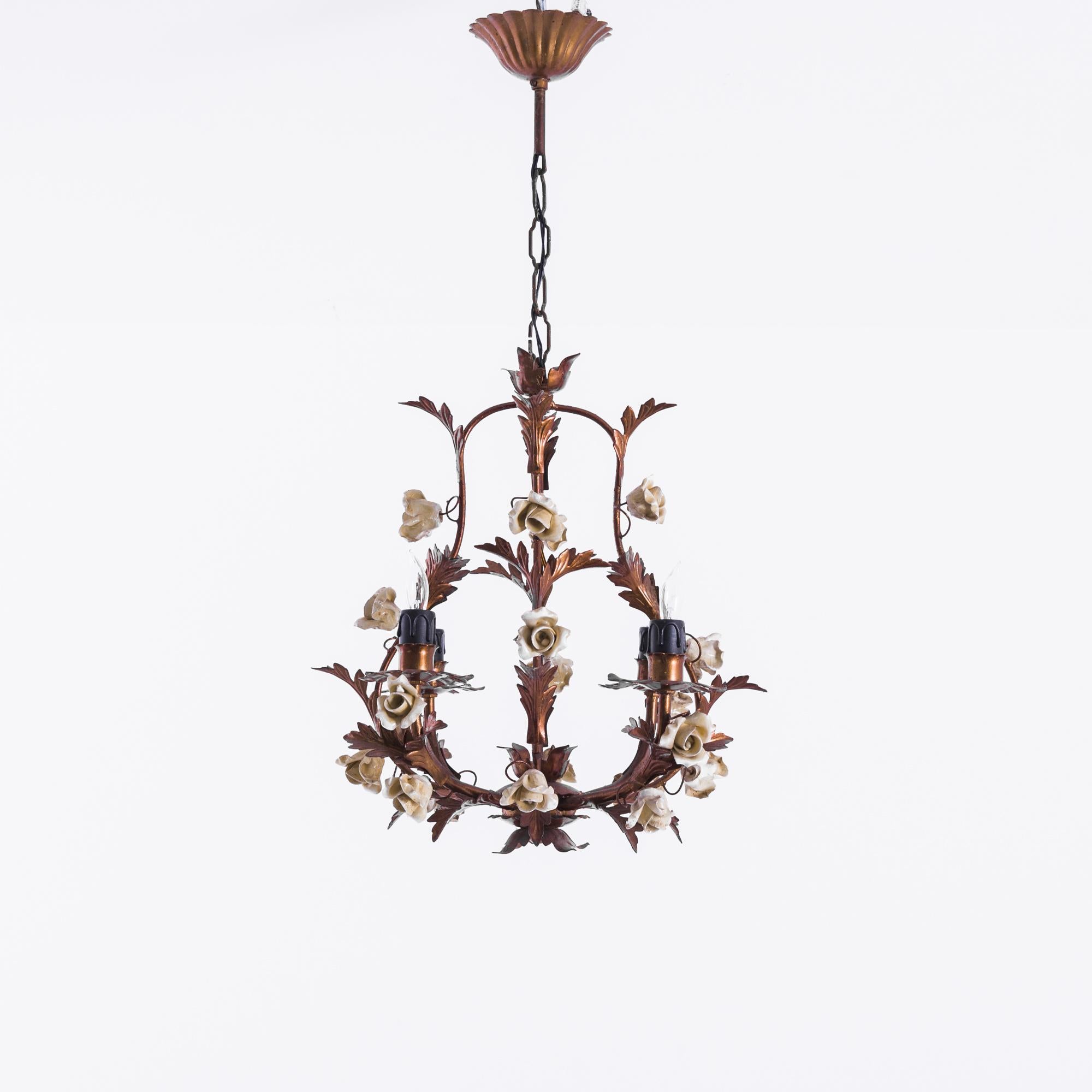 A metal chandelier from 1960s France. Unruly and romantic. Lifelike metal flowers and leaves resemble roses trelessed around four upraised arms bearing candle bulbs. The sconces are embellished with petals and sepals, framing the light fixtures like