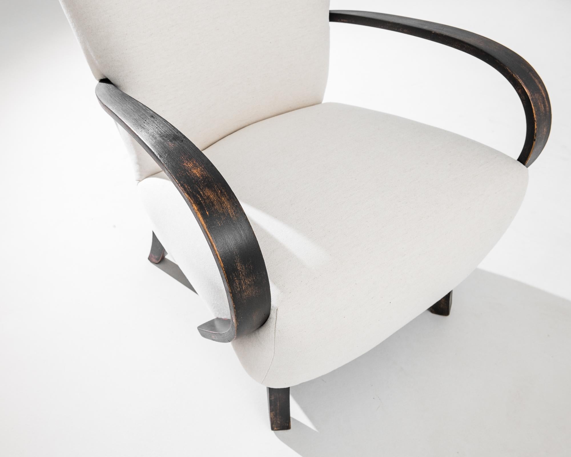 Transform your living space with this exquisite pair of 1960s French Upholstered Armchairs. These elegant pieces feature gracefully curved wooden armrests and legs, embodying the charm of mid-century French design. The chairs are upholstered in a