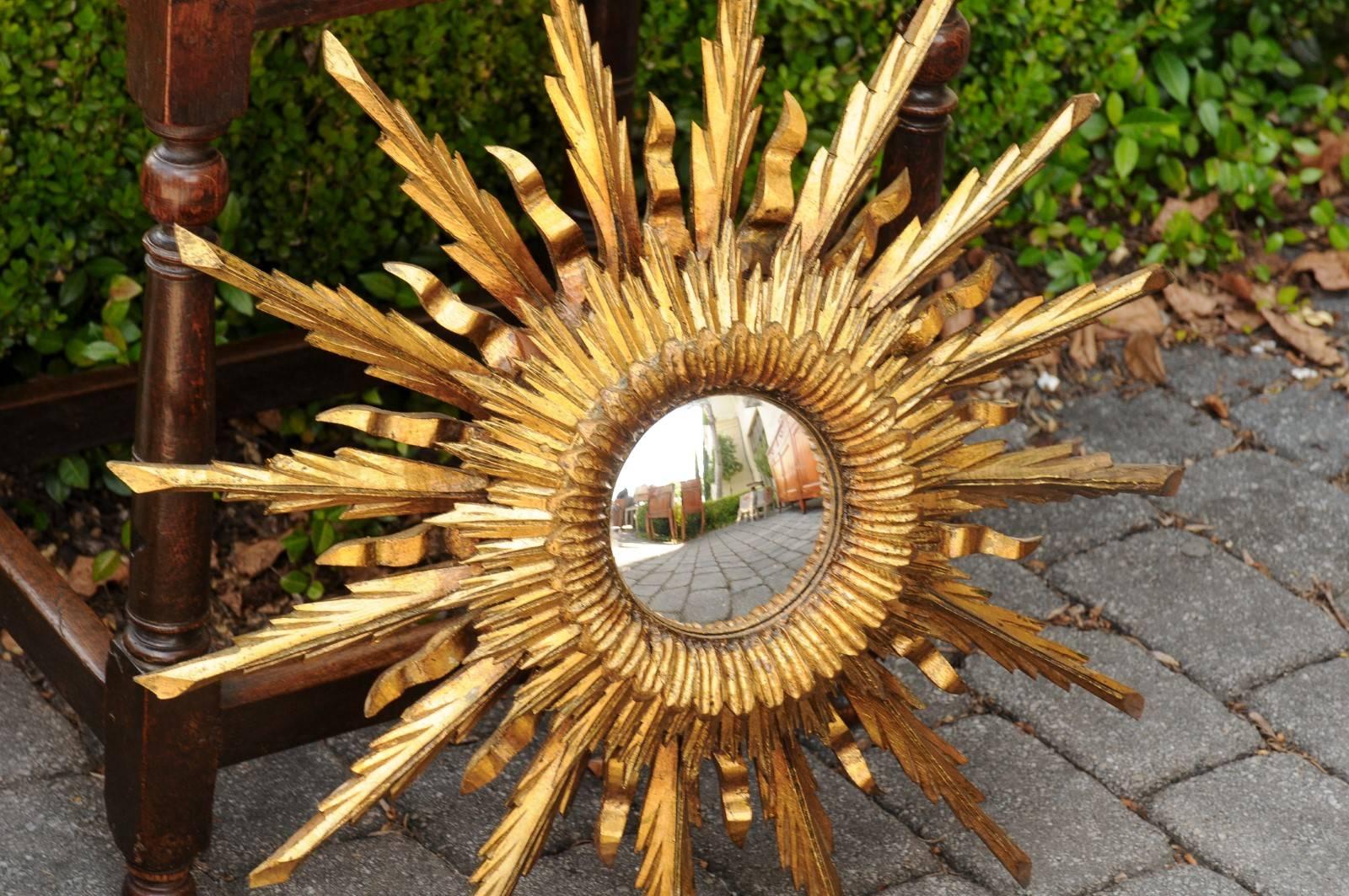 A vintage French 1960s giltwood three-layered sunburst mirror with convex mirror plate. This French sunburst mirror features a central convex mirror plate offering a lovely distortion of images. This mirror is directly surrounded by carved leaves