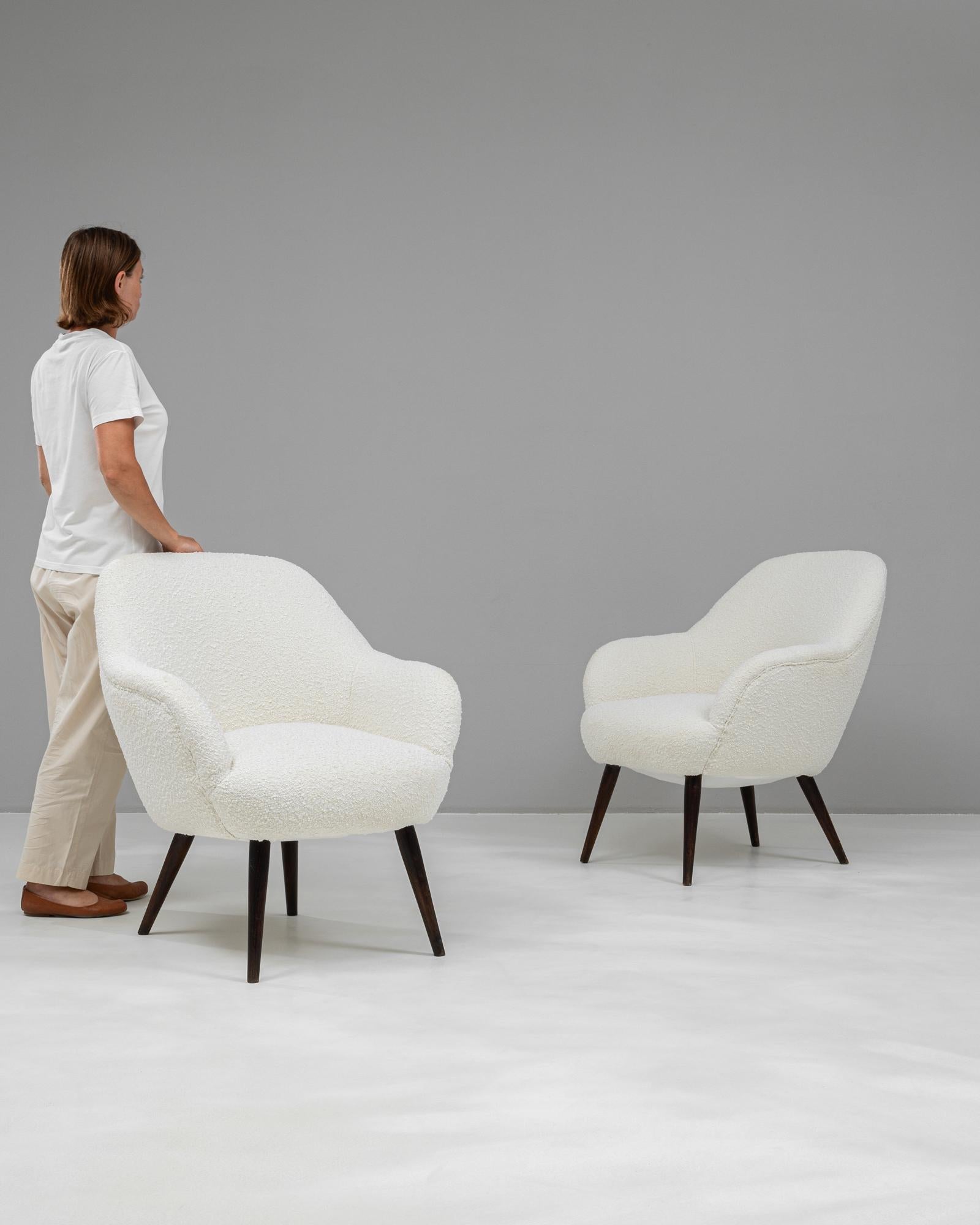 This pair of mid-century armchairs from 1960s Czechia showcases timeless elegance with their sculptural curves and minimalist design. Upholstered in a luxurious, textured white boucle fabric, they bring a touch of refined sophistication to any