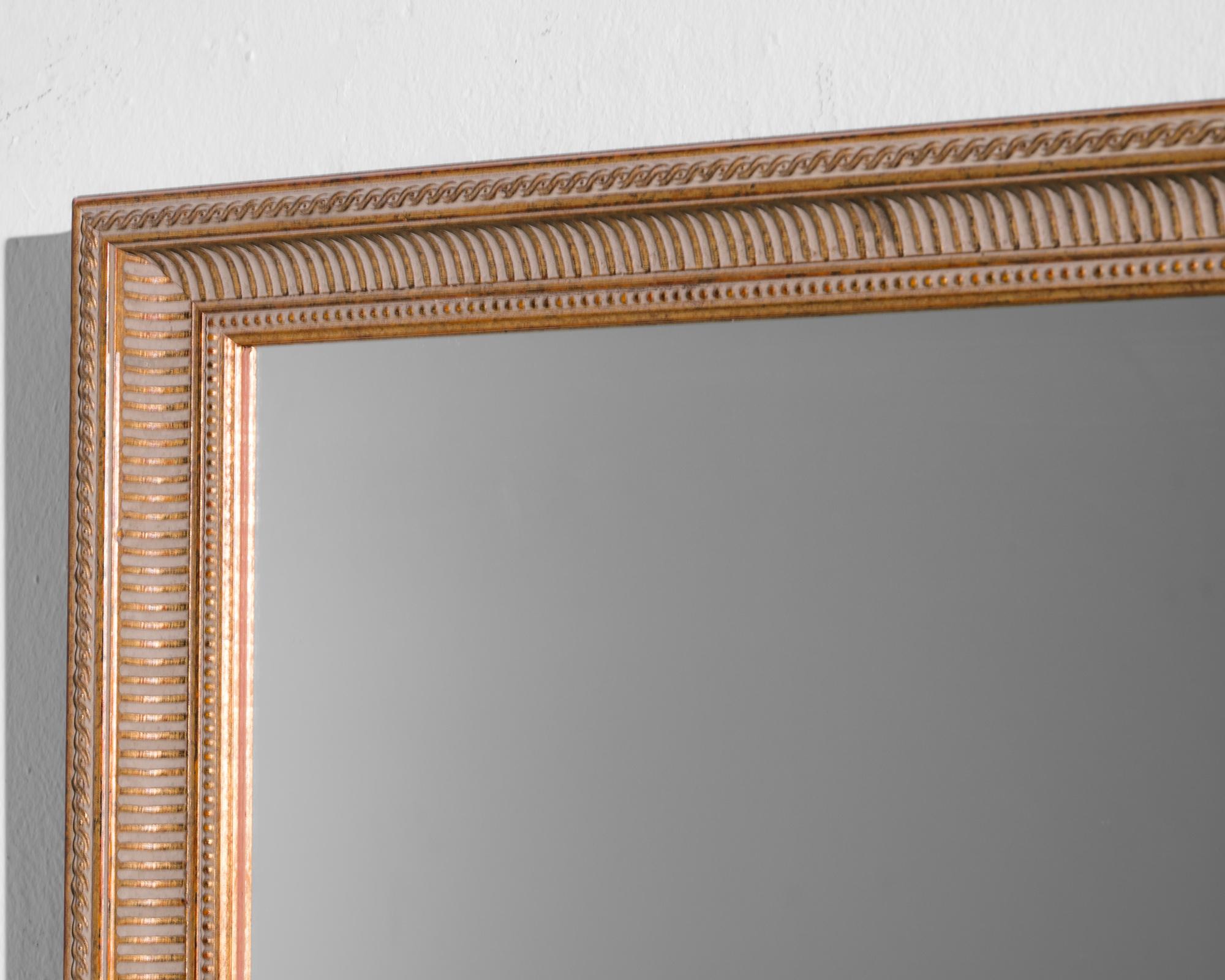 Infuse your space with the chic elegance of this 1960s French Wooden Mirror. The mirror boasts a warm tan hue that radiates a subtle charm, creating a cozy and inviting atmosphere. Accentuating its timeless appeal are the intricate gold accents