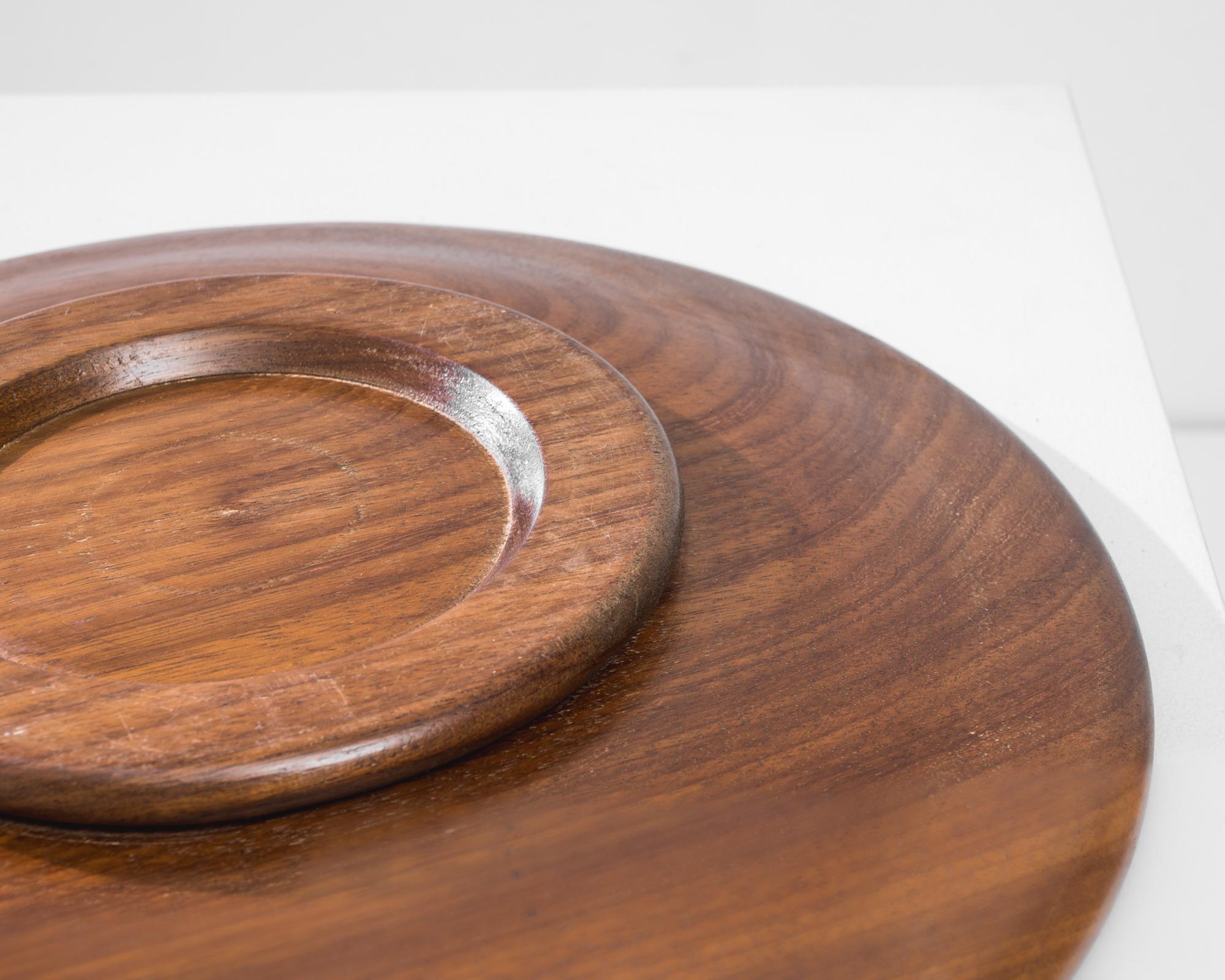 This vintage wooden plate was crafted in France, circa 1960. Beautifully patinated, the wood displays a rich chocolate tone and a lush shine. Masterfully carved, the quality of the wood is shown through harmonious concentric circles and a seamless