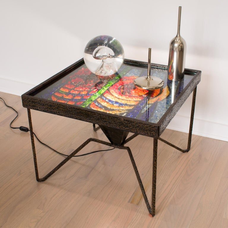 Elegantly crafted one-of-a-kind 1960s coffee or side table. This cocktail table features eye-catching chunks of glass geometric mosaic top encased in a textured wrought iron table base with spider-shaped legs. The mosaic is protected by a glass