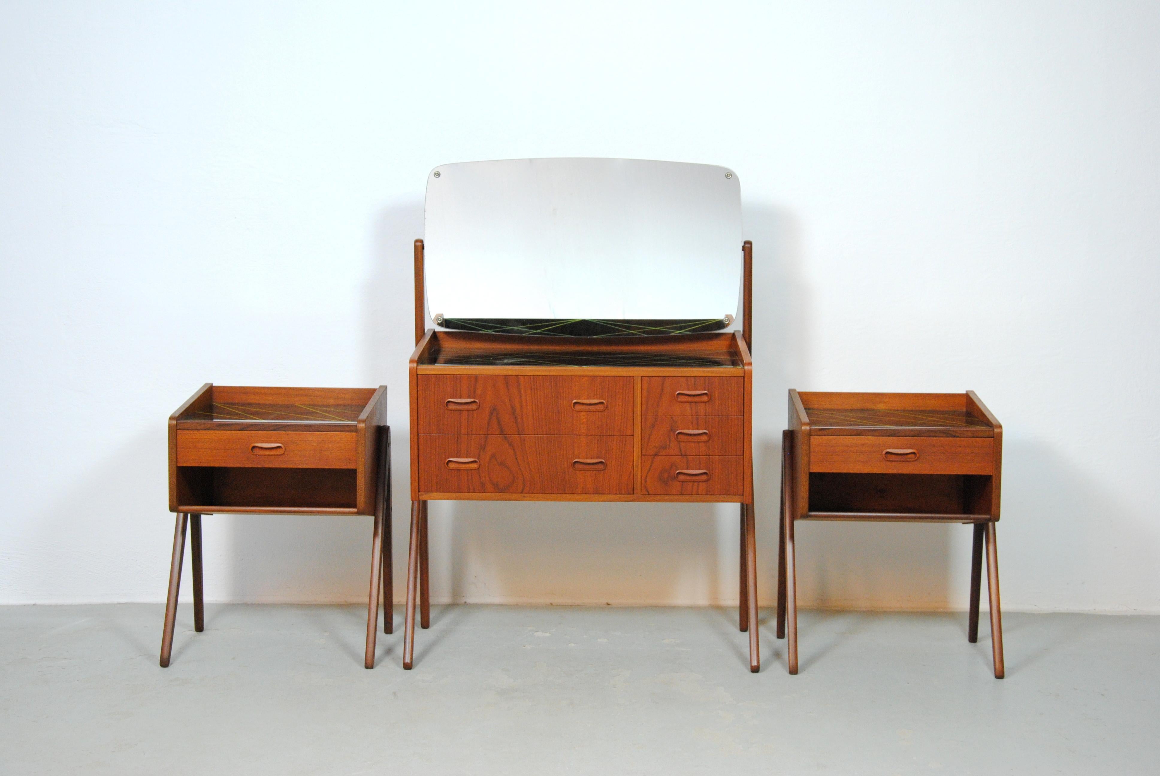 1960s teak vanity table and two nightstands with decorated glass tabletops

The rarely seen set feature a fully restored teak vanity table with a large adjustable mirror, a black glass table top decorated with colored patterns, 5 spacious drawers
