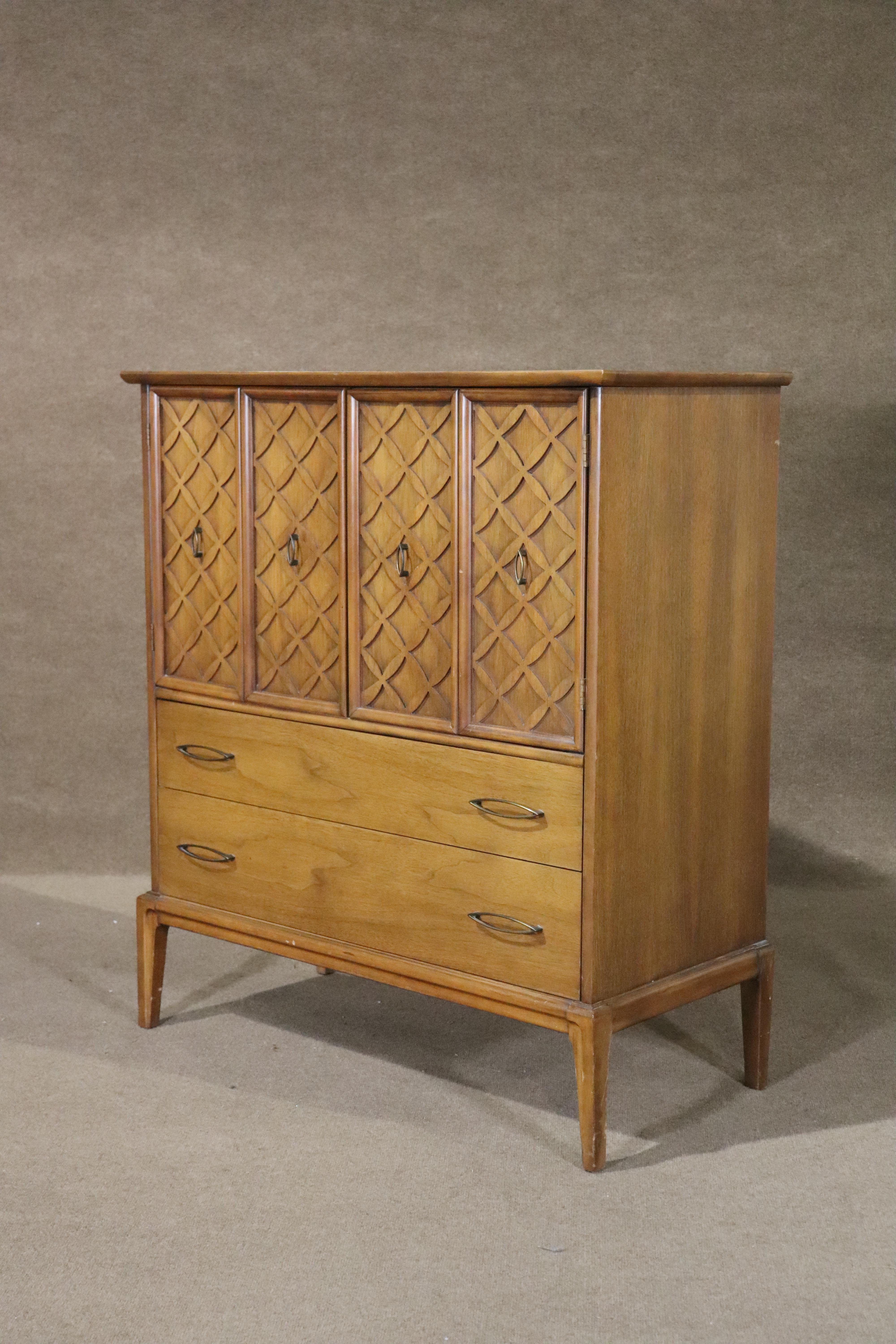 Mid-century modern chest of drawers in walnut with brass cat eye handles and lattice front doors. Drawers plus storage space give you options for your bedroom.
Please confirm location NY or NJ