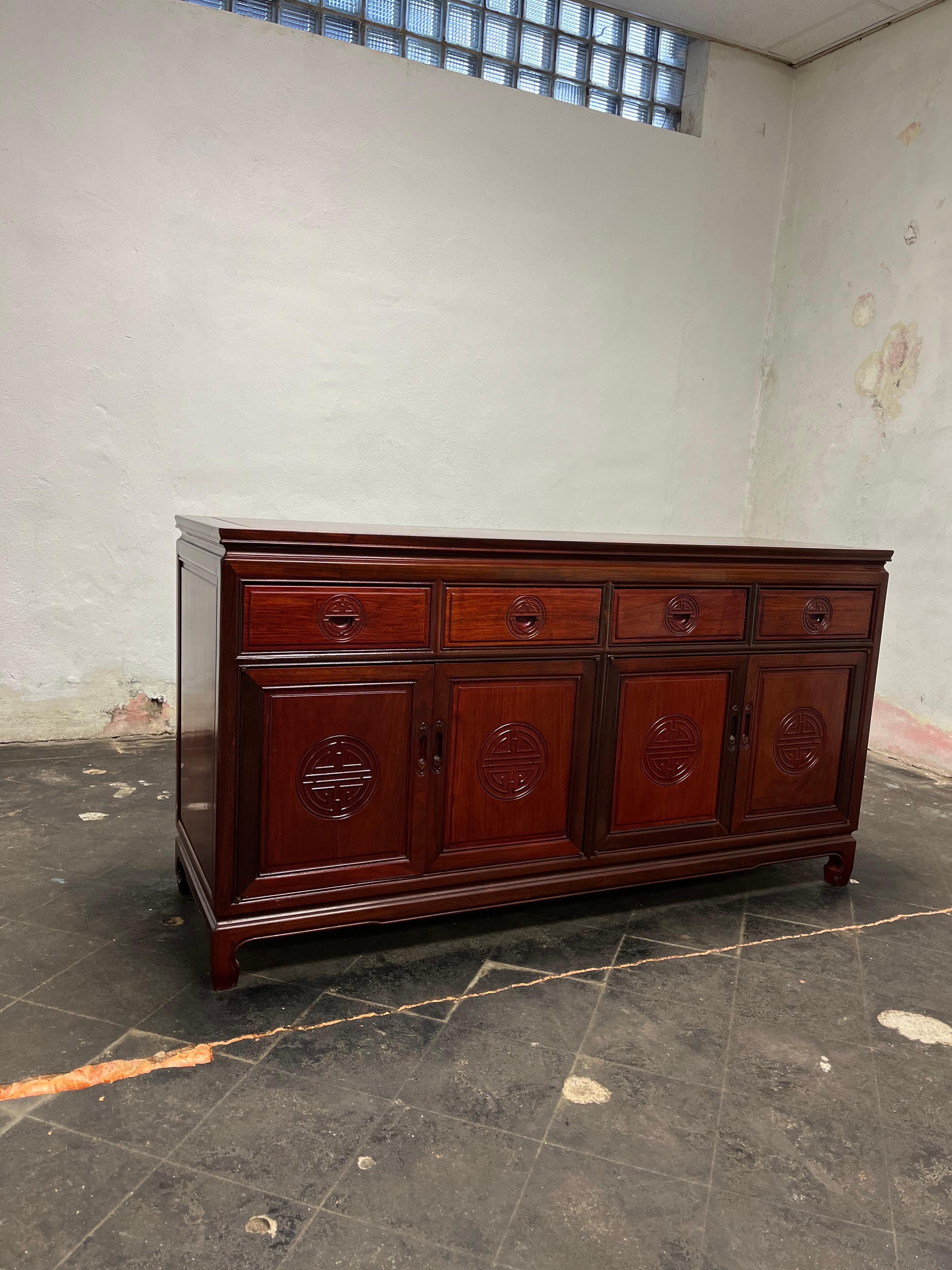 Handsome solid rosewood Chinoiserie Hollywood Regency buffet or credenza by George Zee. It is in fabulous vintage condition. Four drawers with four door front that house lower shelving. Finished back to allow for floating in the room. It has no