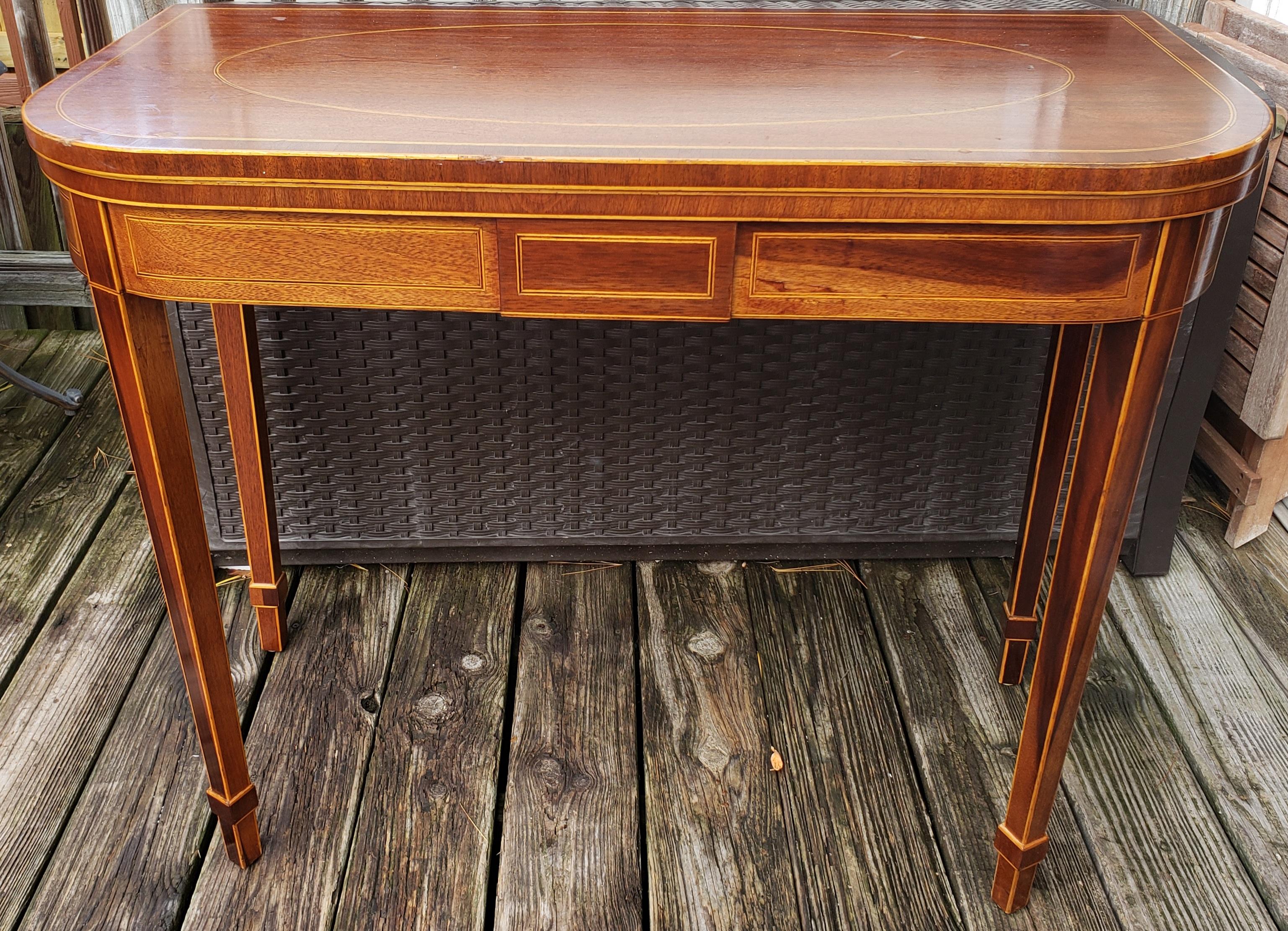 Fabriquée en bel acajou, cette console présente des incrustations en bois de satin sculpté sur le dessus, les pieds et les panneaux latéraux. La table s'ouvre sur un magnifique plateau fini en bandes en très bon état. La table est soutenue par