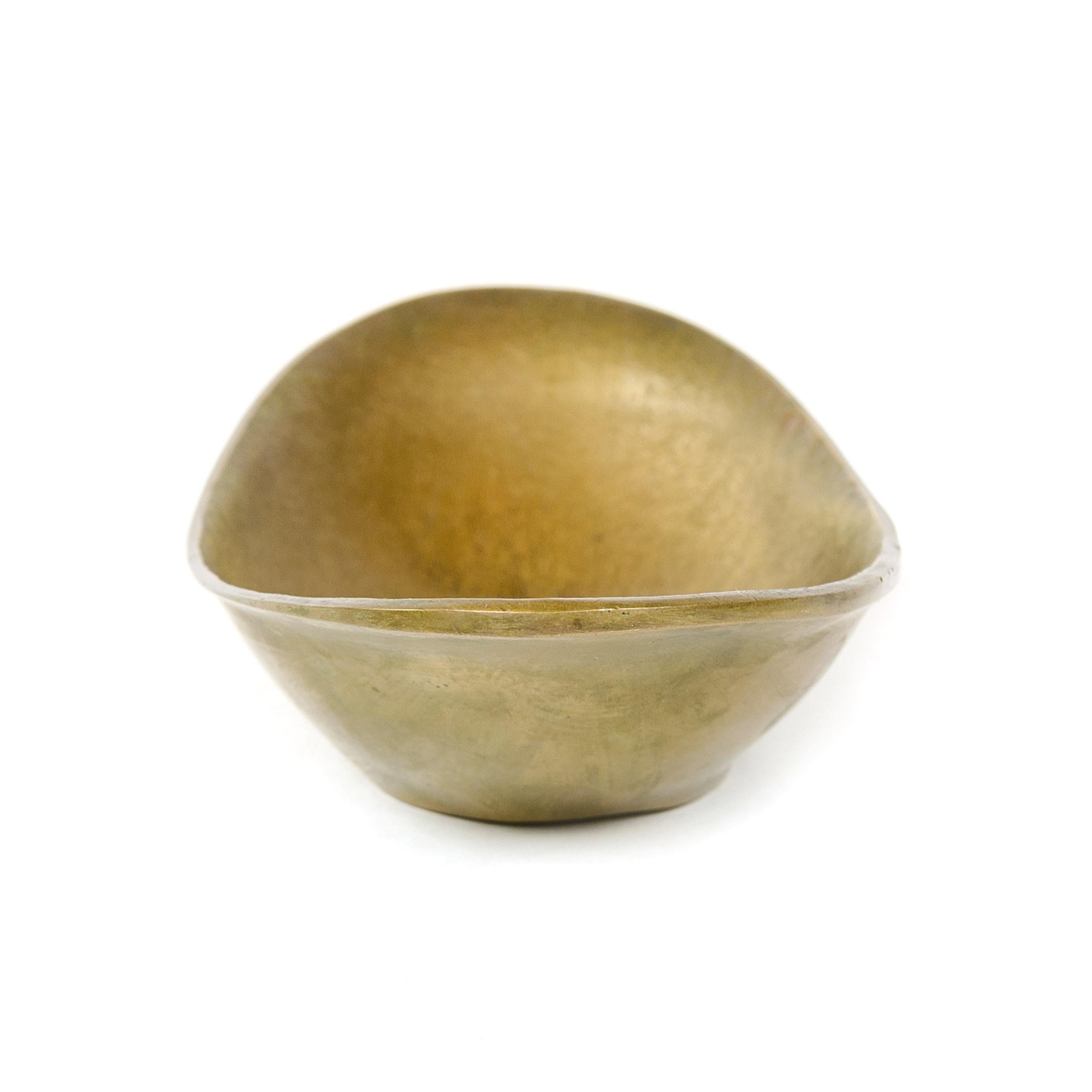 Low, boat-shaped oval bowl of solid brass. The bowl's interior displays a subtle, finely incised design which radiates from the center of the bowl to its outer edges. 'Made in Germany' in block letters is impressed on the underside.