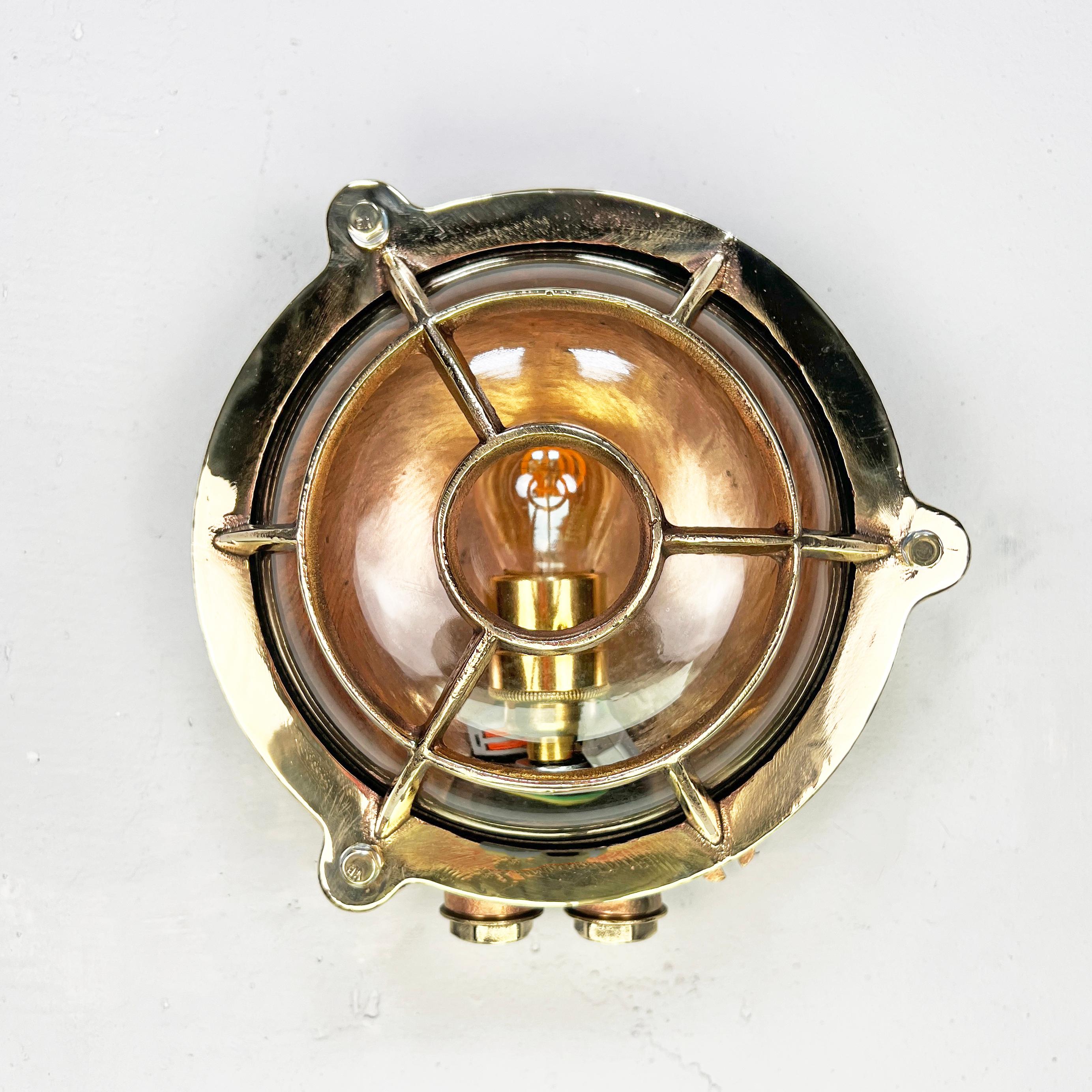 Una luz marina original de latón, recuperada y restaurada profesionalmente. Este aplique redondo vintage presenta una jaula en forma de diana diseñada para proteger el portalámparas junto con la cúpula de cristal templado. Un auténtico aplique
