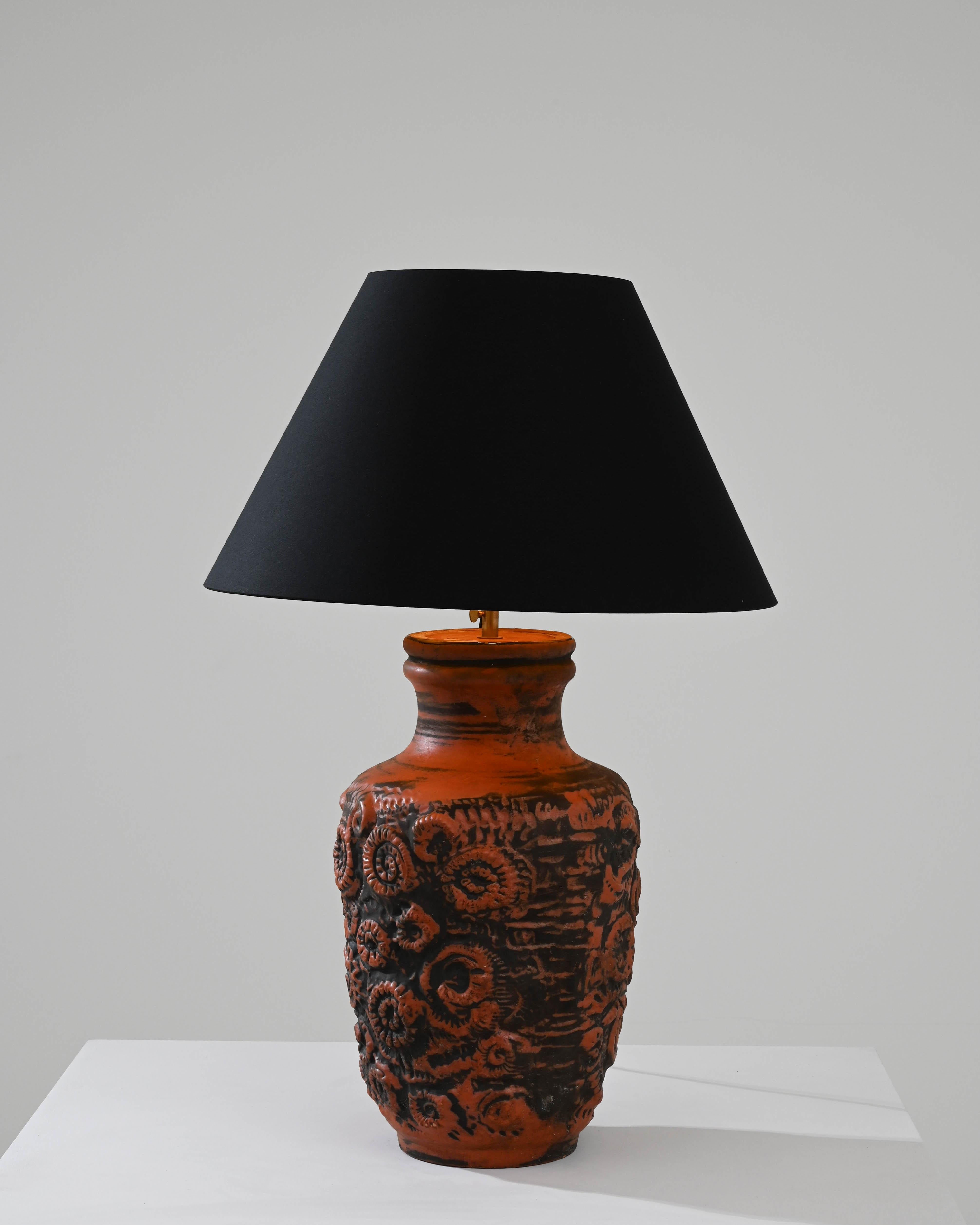 Illuminate your space with the timeless charm of this 1960s German Ceramic Table Lamp. The lamp's base, adorned in a sophisticated earthy hue reminiscent of aged copper, exudes a rich and elegant presence. Delicate carvings of fossil ammonites