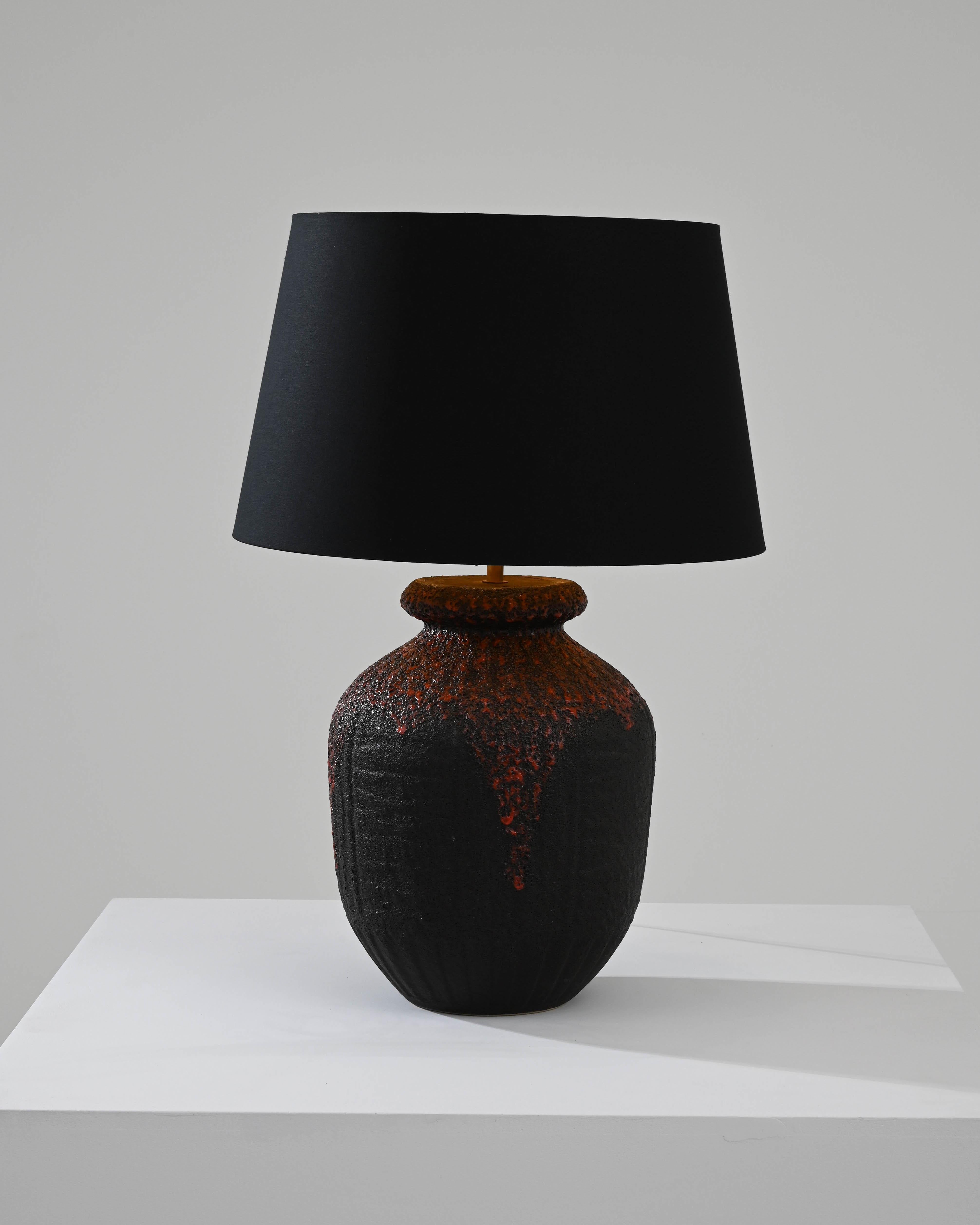 Enrich your living space with the captivating allure of this 1960s German Ceramic Table Lamp. The lamp features a textured black base that exudes a sense of sophistication and depth. Transitioning seamlessly, the top of the base introduces a vibrant
