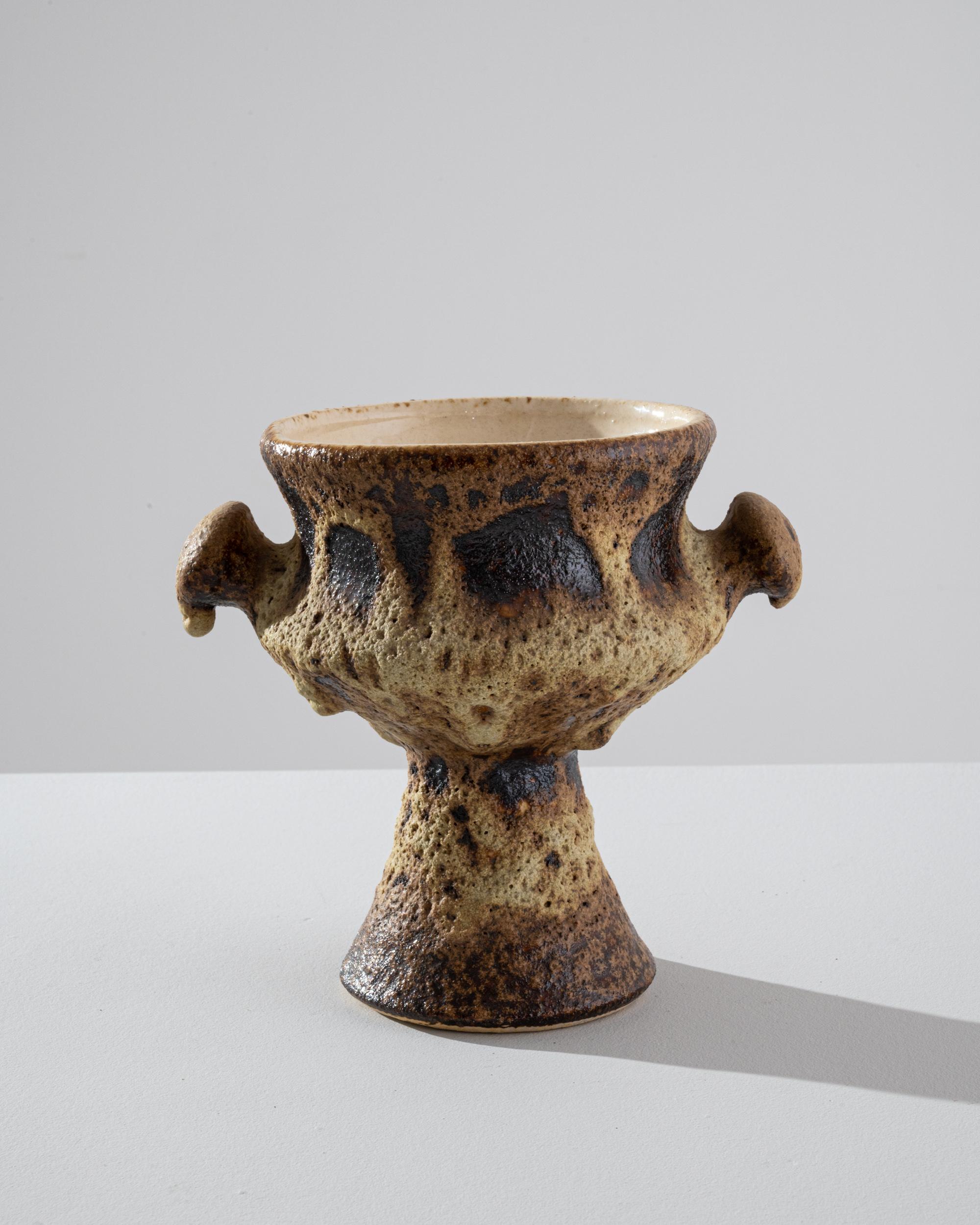 Fascinatingly tactile, this vintage vase offers a unique vision of the potter. Made in Germany in the 1960s, the form is that of a traditional goblet, flanked by nubby handles; an alchemical glaze distorts and warps the silhouette into something