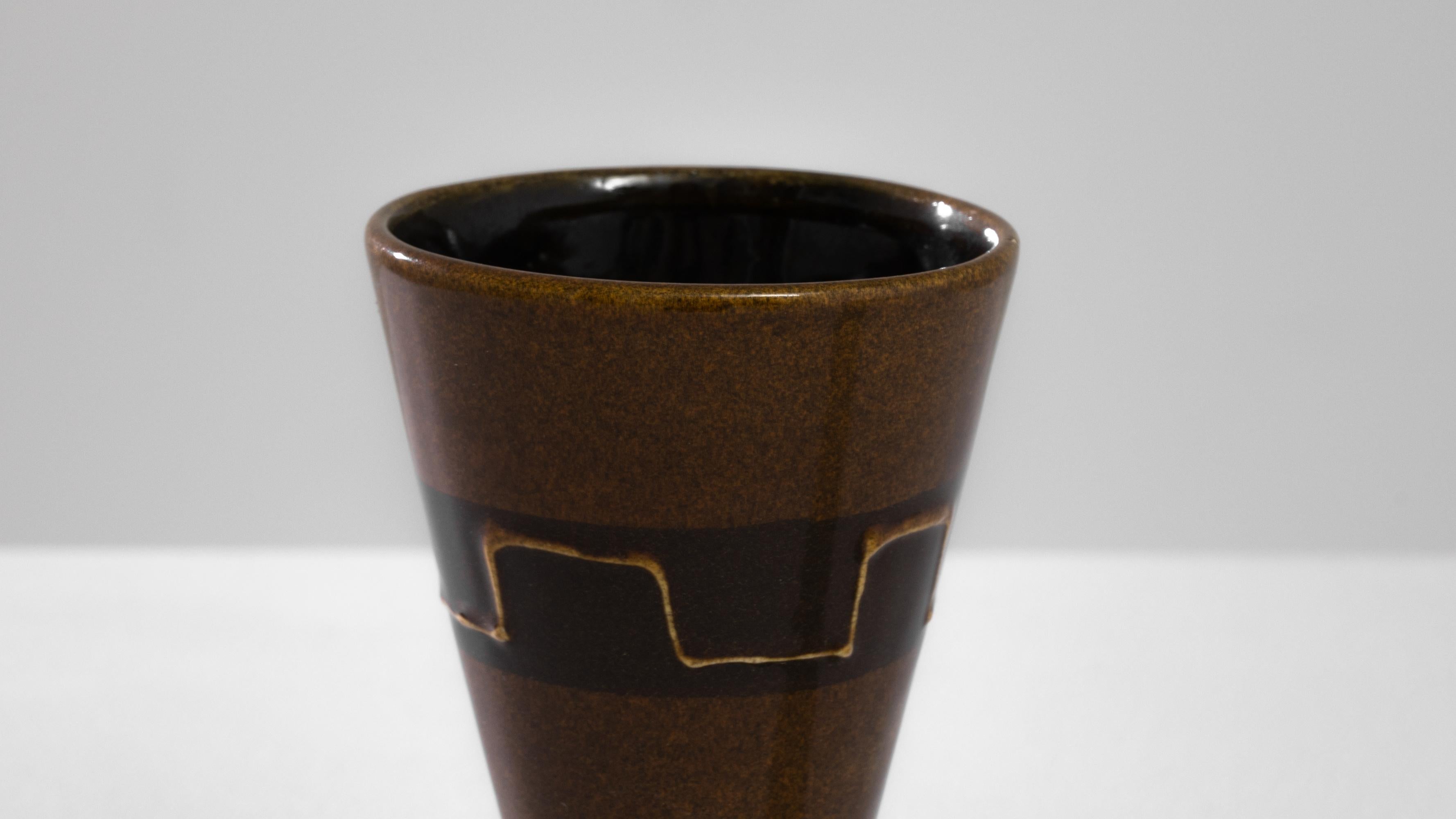 Embrace the unique aesthetic of the 1960s with this German ceramic vase, featuring a captivating concave structural design. The vase, adorned in a rich brown hue, exudes a warm and earthy feel. Its surface is embellished with intricate line designs,
