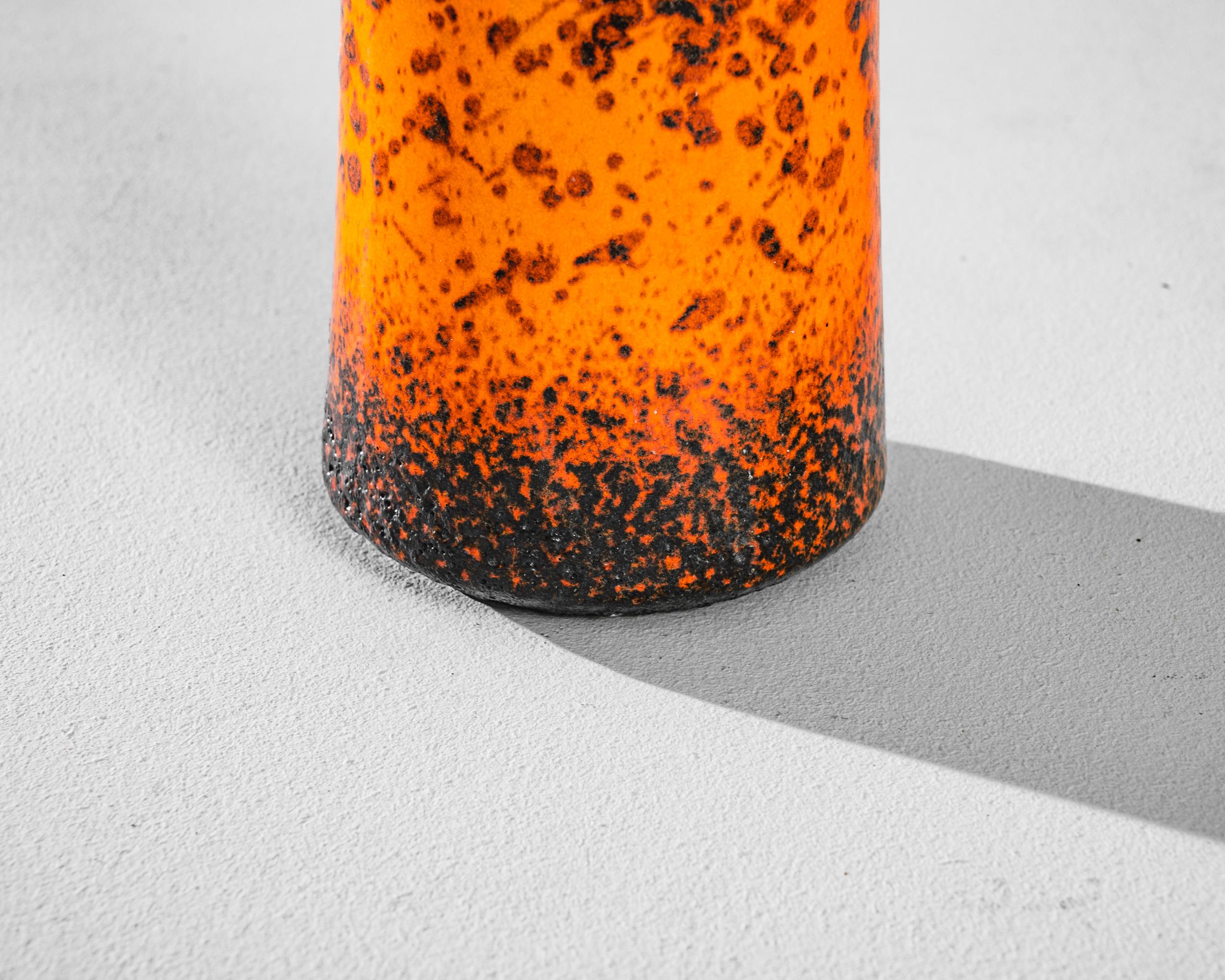 Immerse your space in the vibrant spirit of the 1960s with this German ceramic vase. The lively orange hue sets an energetic tone, while the playful black splatter paint creates a dynamic and artistic effect across the surface. The strategic