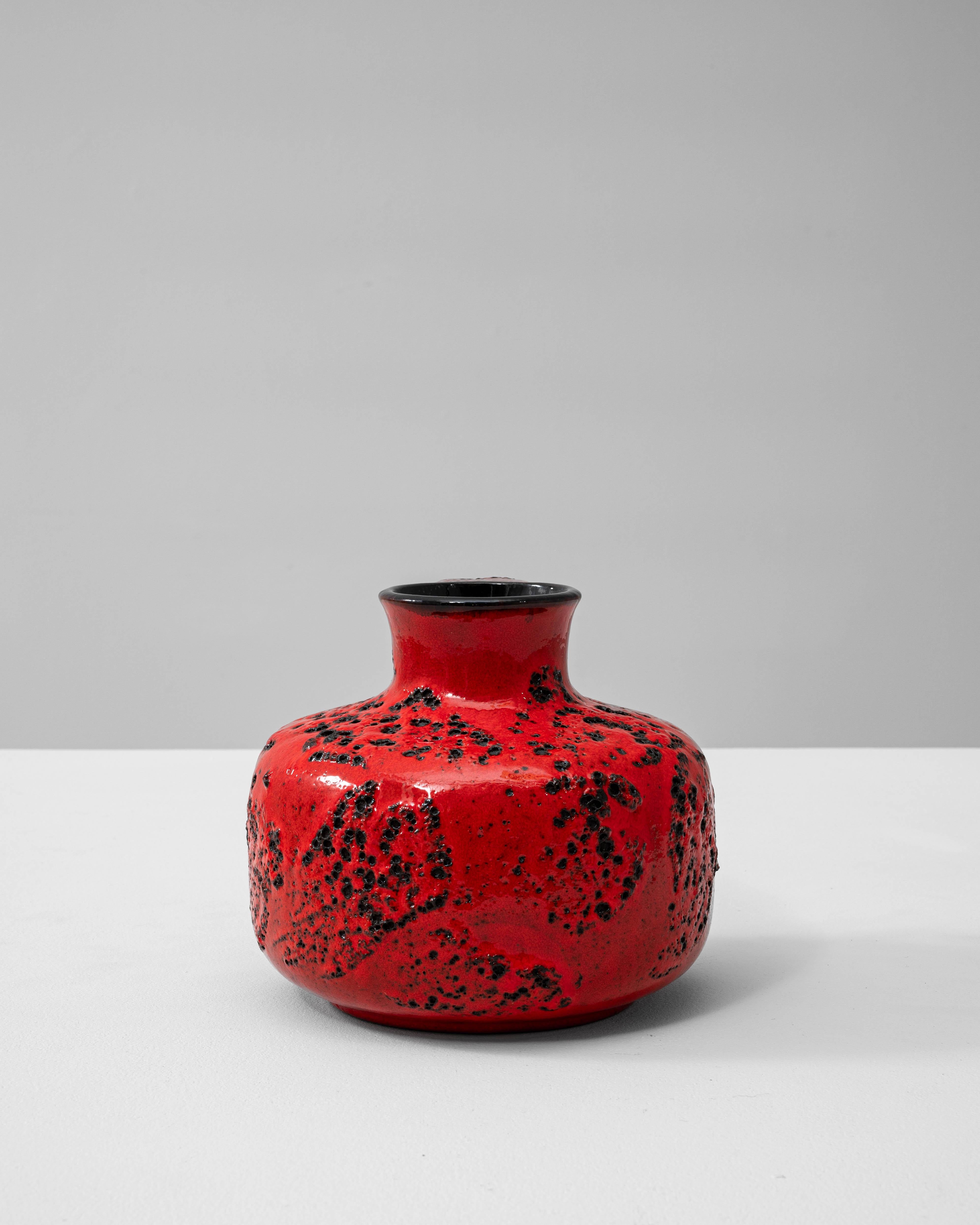 Questo vaso in ceramica tedesca degli anni '60 esemplifica l'audace creatività del movimento della ceramica Fat Lava. Il suo sorprendente smalto rosso è accentuato da profonde eruzioni nere, creando una superficie vulcanica e dinamica che conferisce
