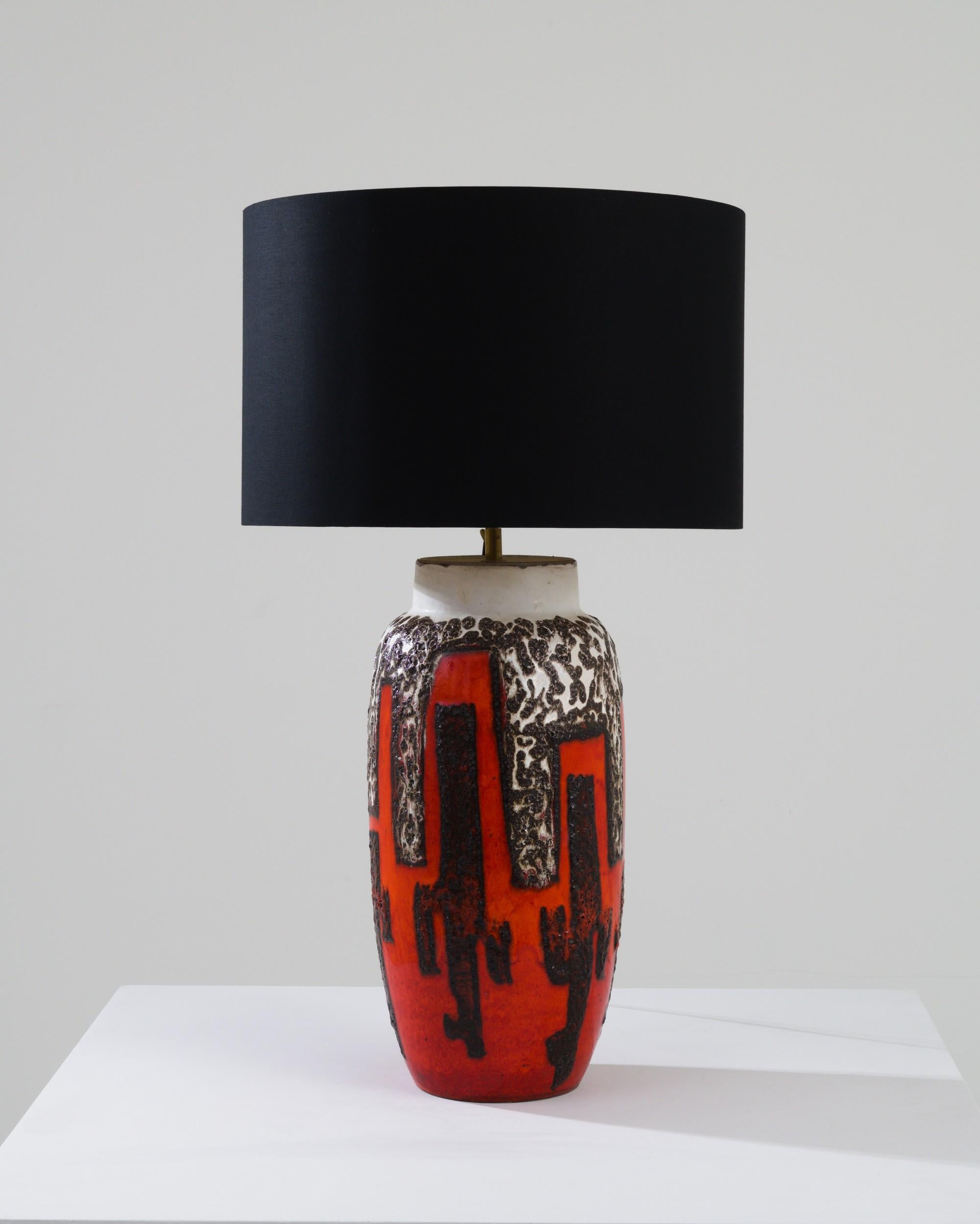 Designed in 1960s Germany, this distinctive lamp boasts a shallow, black lampshade held by a meticulously handcrafted ceramic base. The striking geometric patterns, adorned in vibrant hues reminiscent of the motifs found in abstract expressionist