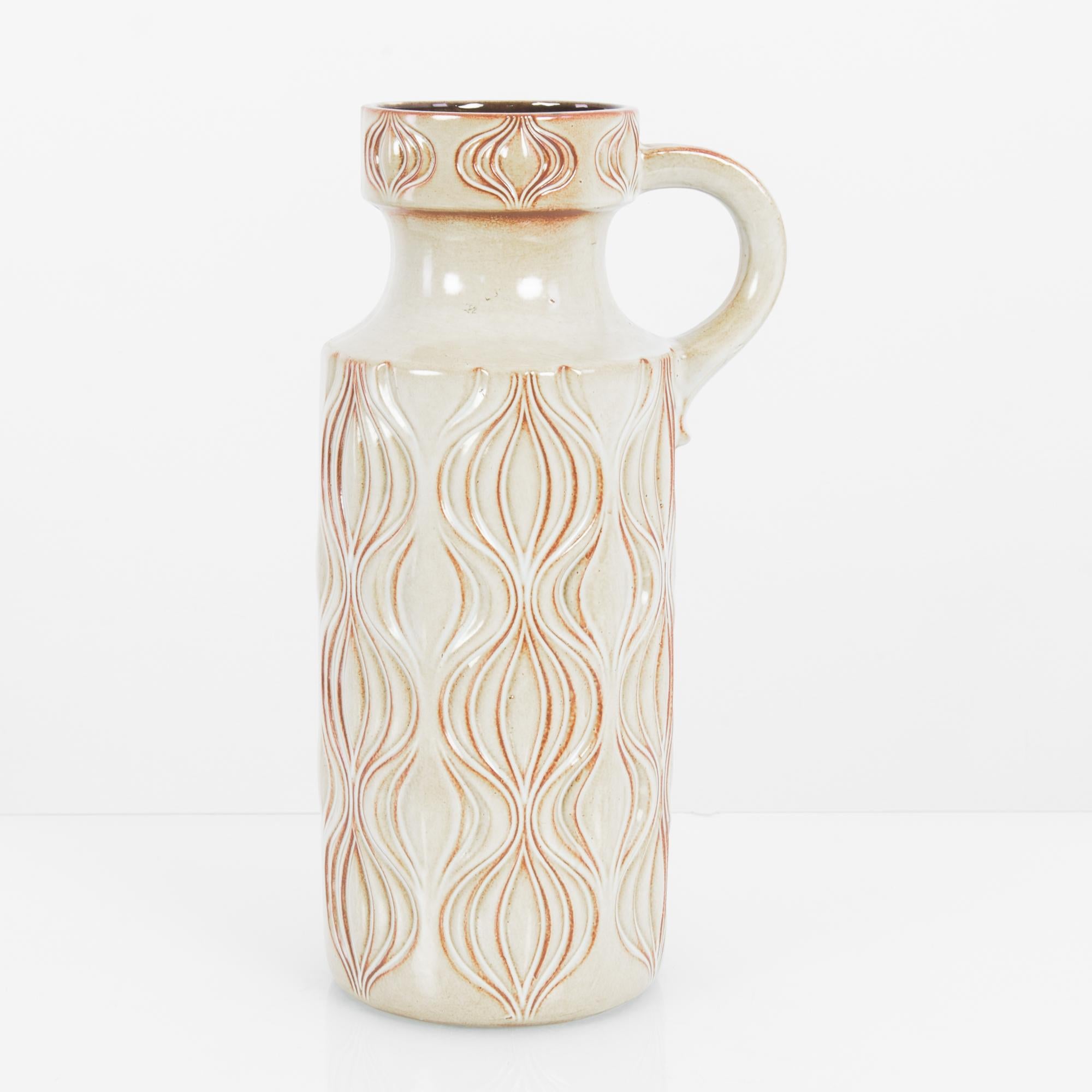 A ceramic vase from West Germany, circa 1960. An upright flask of white ceramic is decorated with a raised pattern, rippling and fluid, reminiscent of onion bulbs or tulips. The raised lines bear a soft tint of rosy orange, a warm shadow which