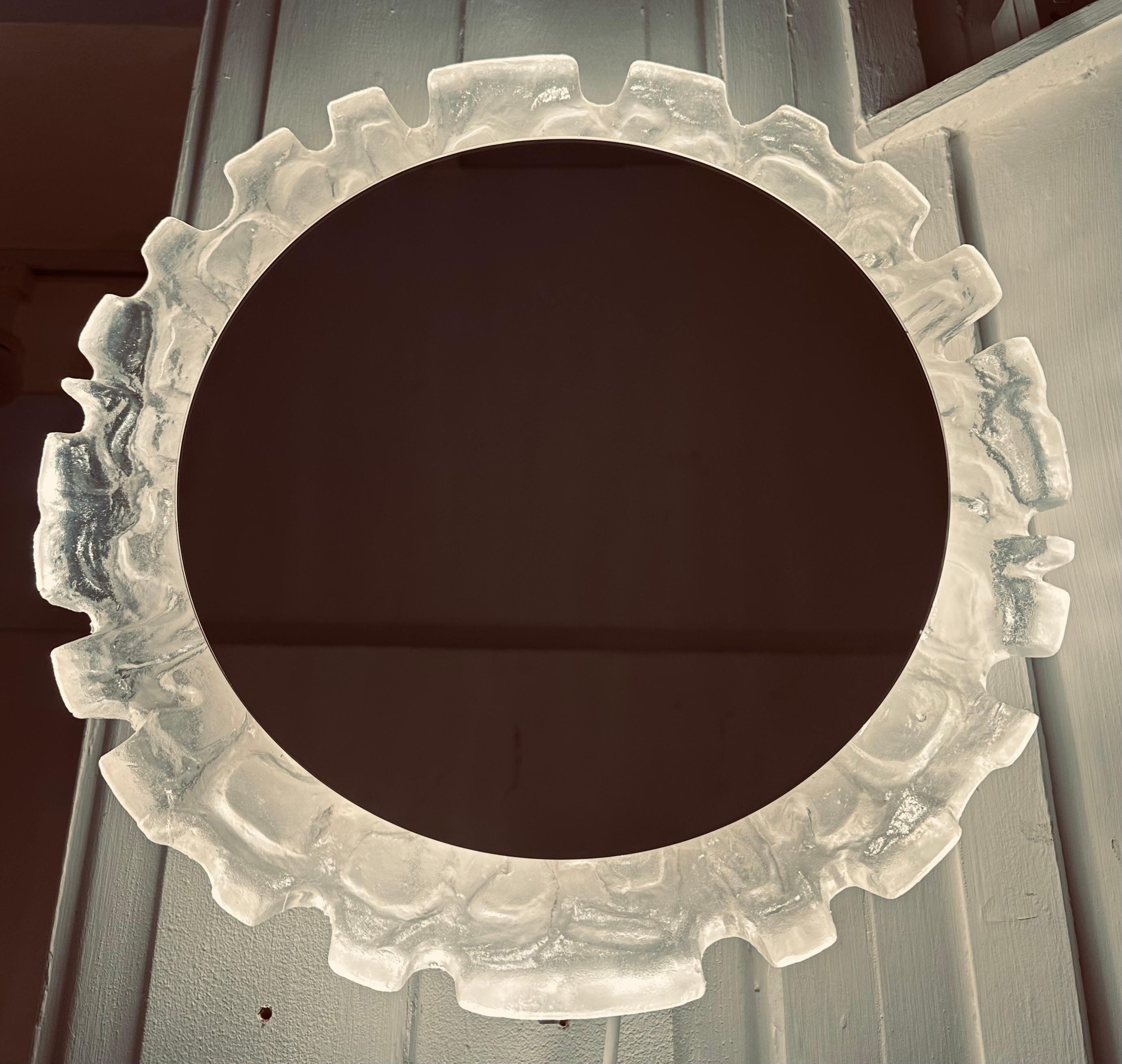 1960s Vintage By German illuminated lucite mirrored glass wall mirror manufactured by Erco.  Le miroir rond est suspendu dans un cadre abstrait en lucite moulé, sculpté et texturé, qui est rétroéclairé.  

Quatre ampoules à vis E14 Edison sont