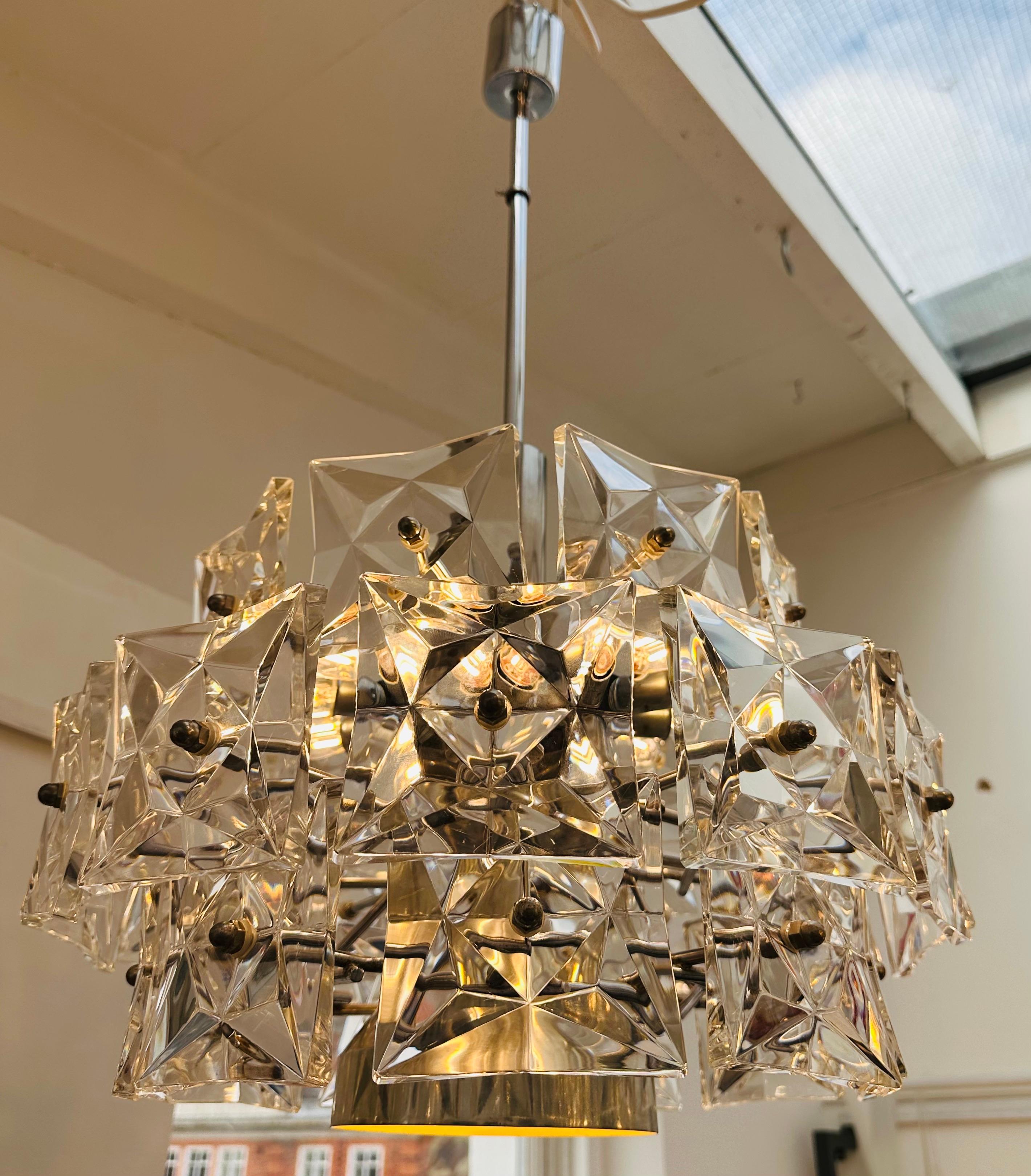 A striking 1960s three-tiered crystal chandelier manufactured by Kinkeldey in Germany. The chandelier is composed of 30 faceted square crystal prisms suspended from a chrome stem and canopy. Each glass prism is secured onto the frame with a feature