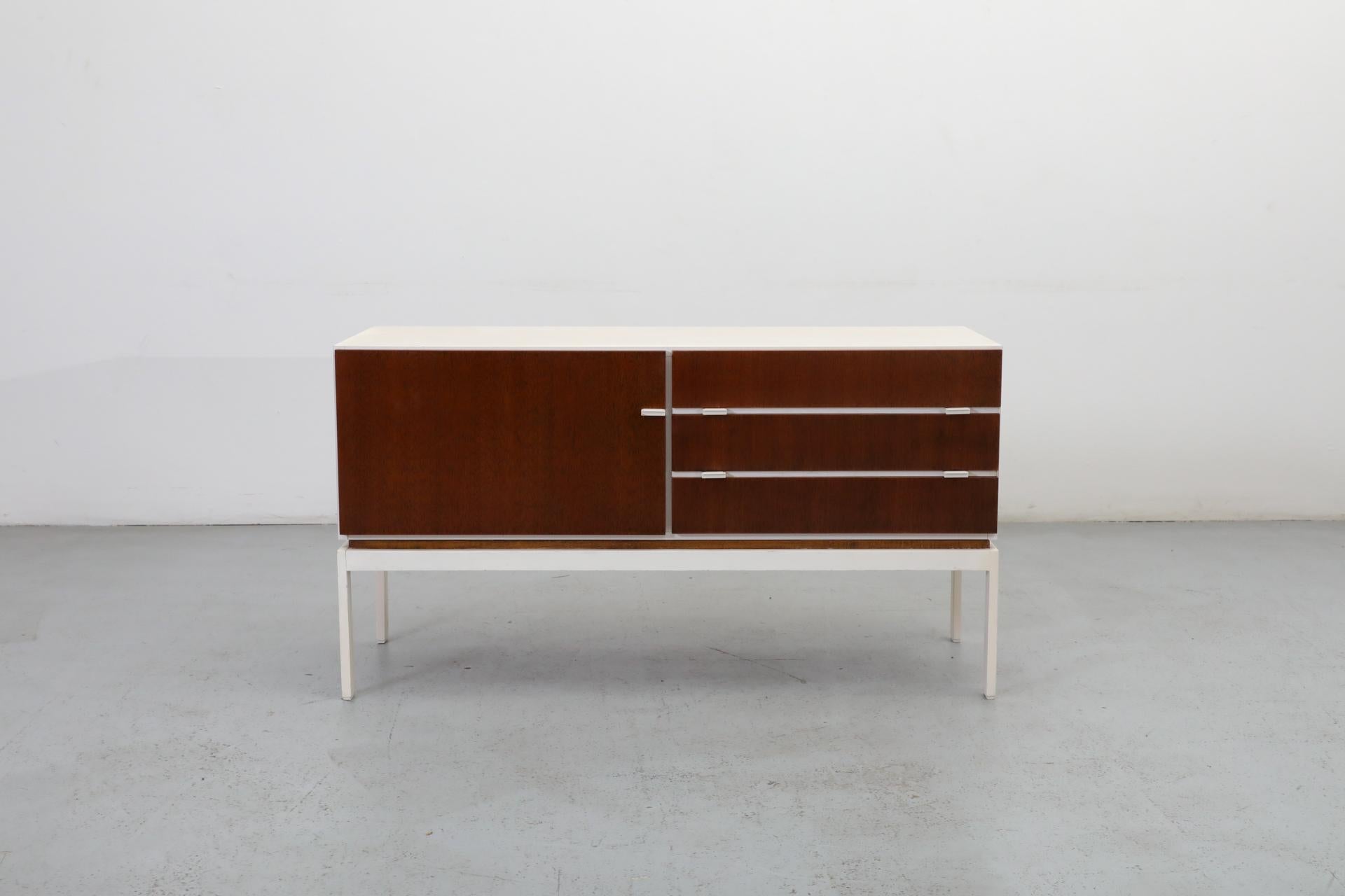 Buffet élégant de style Icone du milieu du siècle, de l'emblématique société allemande d'après-guerre Interlübke, années 1960. Le cadre comporte des portes et des tiroirs plaqués d'acajou et est construit en métal émaillé blanc. En état original