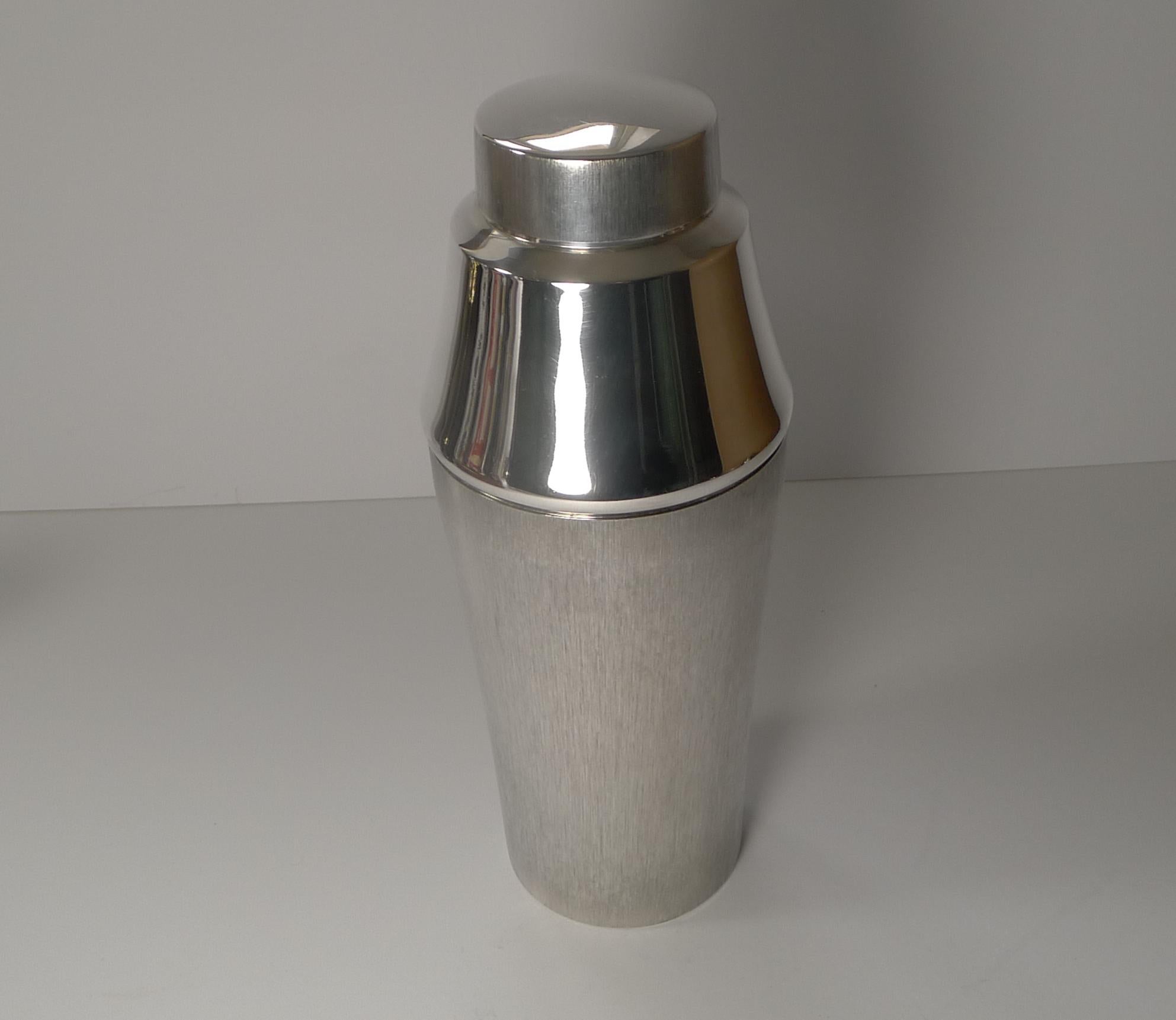 A really stylish retro / vintage cocktail shaker with the body and the lid to the top having a brushed / bark decoration, a lovely combination together with the mirror finish silver plate.

The underside is marked for the silversmith, Lutz and