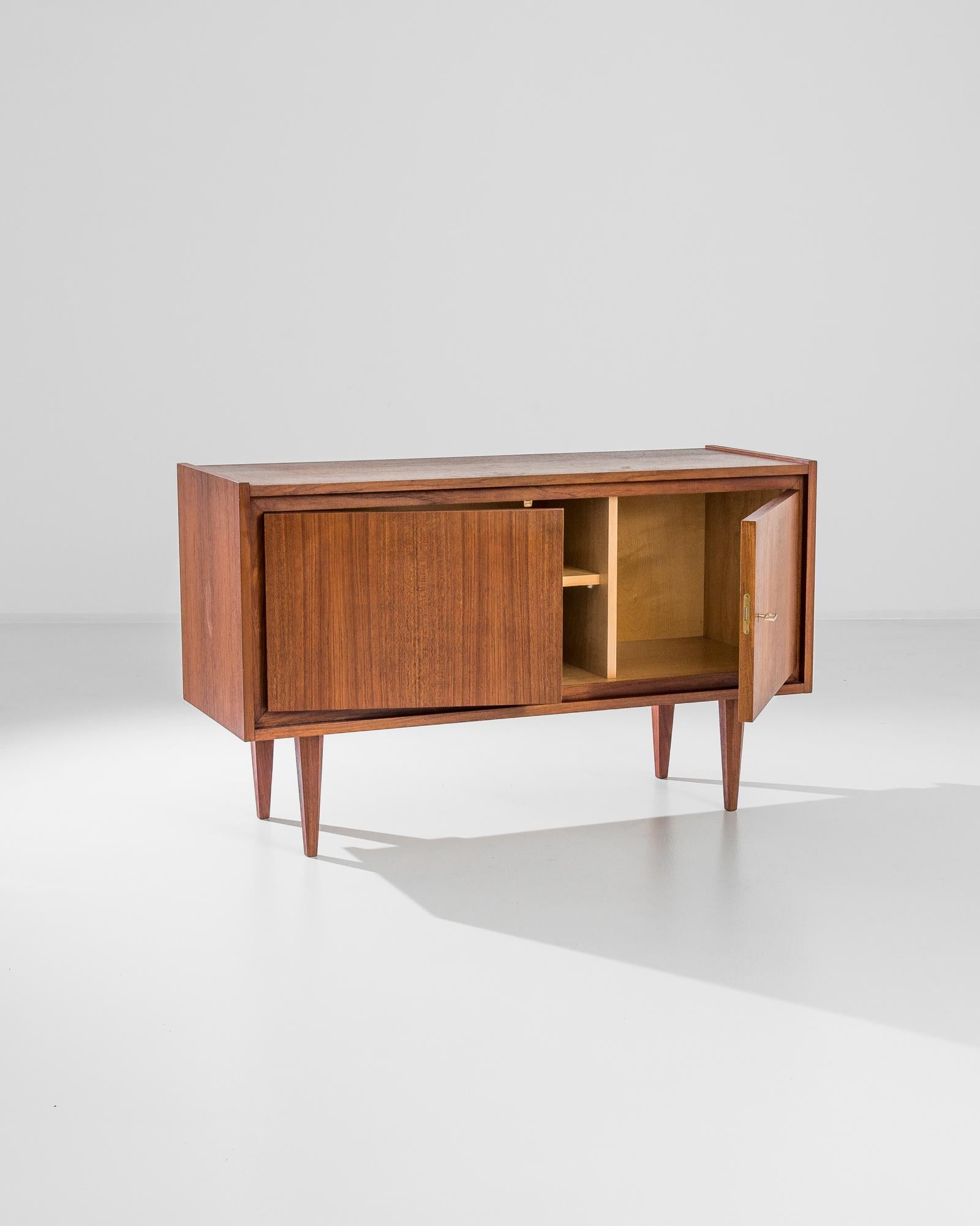 This 1960s German Teak Sideboard is a vintage treasure that offers a blend of utility and sleek design. Constructed from teak, known for its durability and rich grain, the sideboard features a smooth surface and a warm, honeyed finish that has been