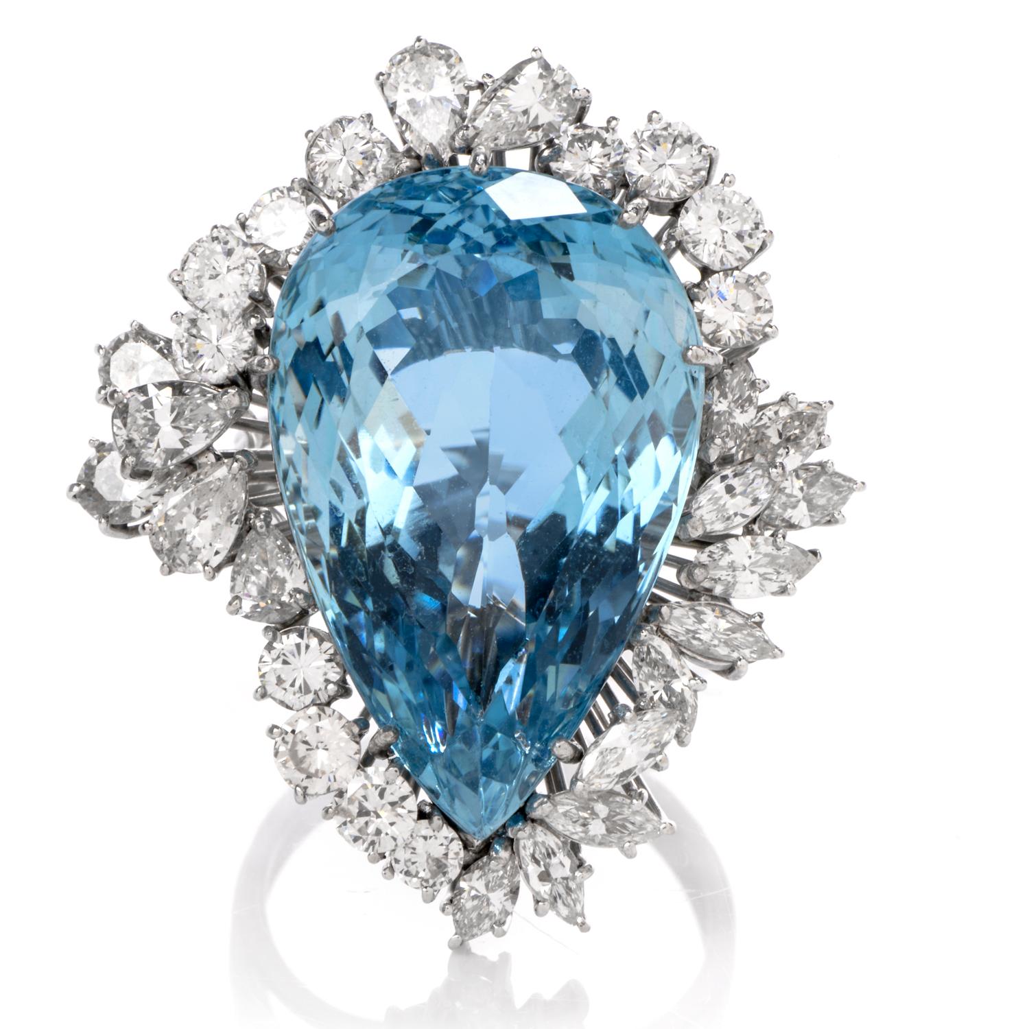 This spectacular floral inspired cocktai ring is hand crafted in luxurious 18K white gold. The center highlight is a remarkable ocean blue colored 23.32ct pear shaped Aquamarine with incredible symmetry and beautifully cut that boasts of color and