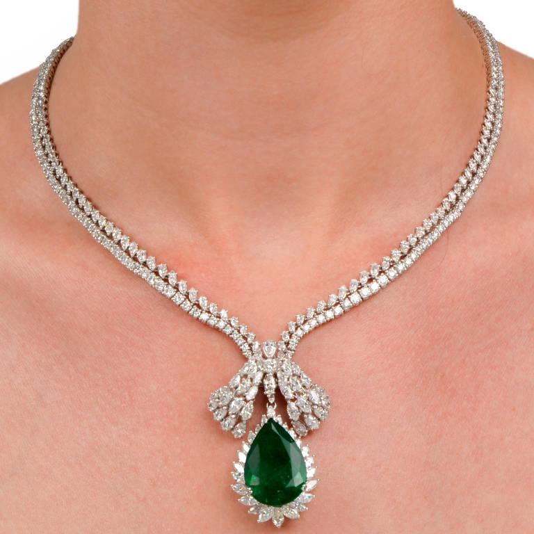 This artistically designed pendant necklace with distinctly cut diamonds and a prominent GIA Certified Genuine emerald is crafted in solid 18K white gold, weighing 68.5 grams and measuring 17.5