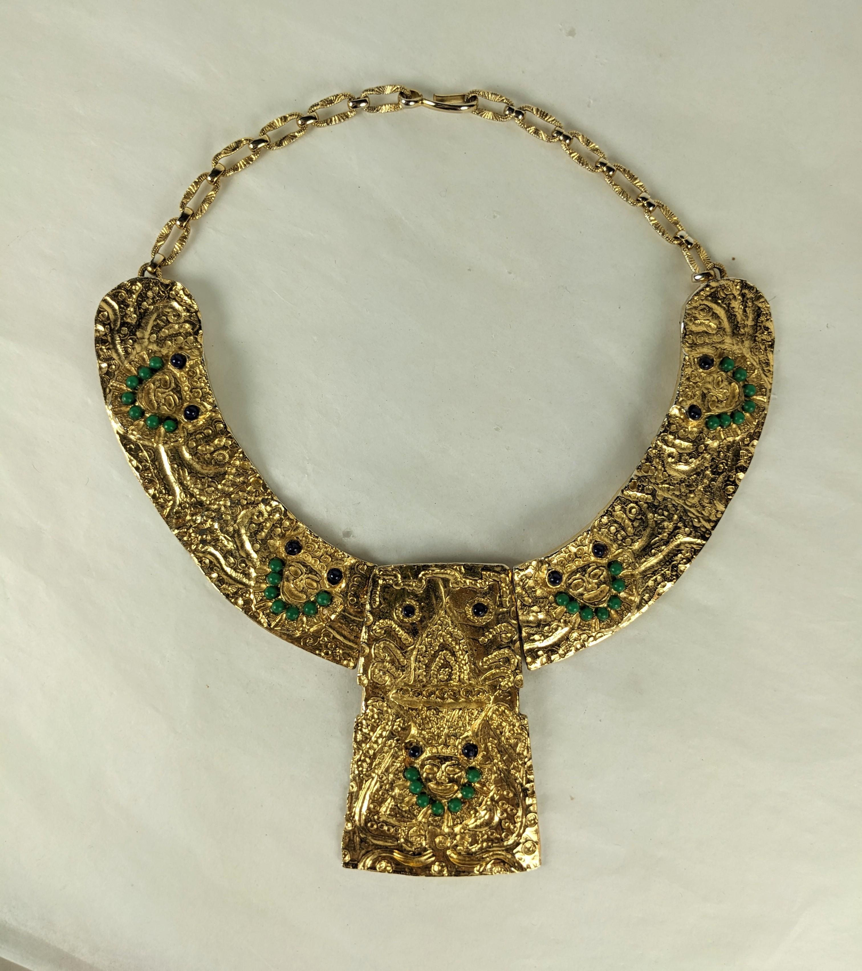 Collier en vermeil des années 1960 avec motifs de masques Pre-Columbian. Le collier rigide est fixé à l'avant par une charnière à la plaque centrale. Métal doré avec des perles noires et vertes. Pièce centrale de 3