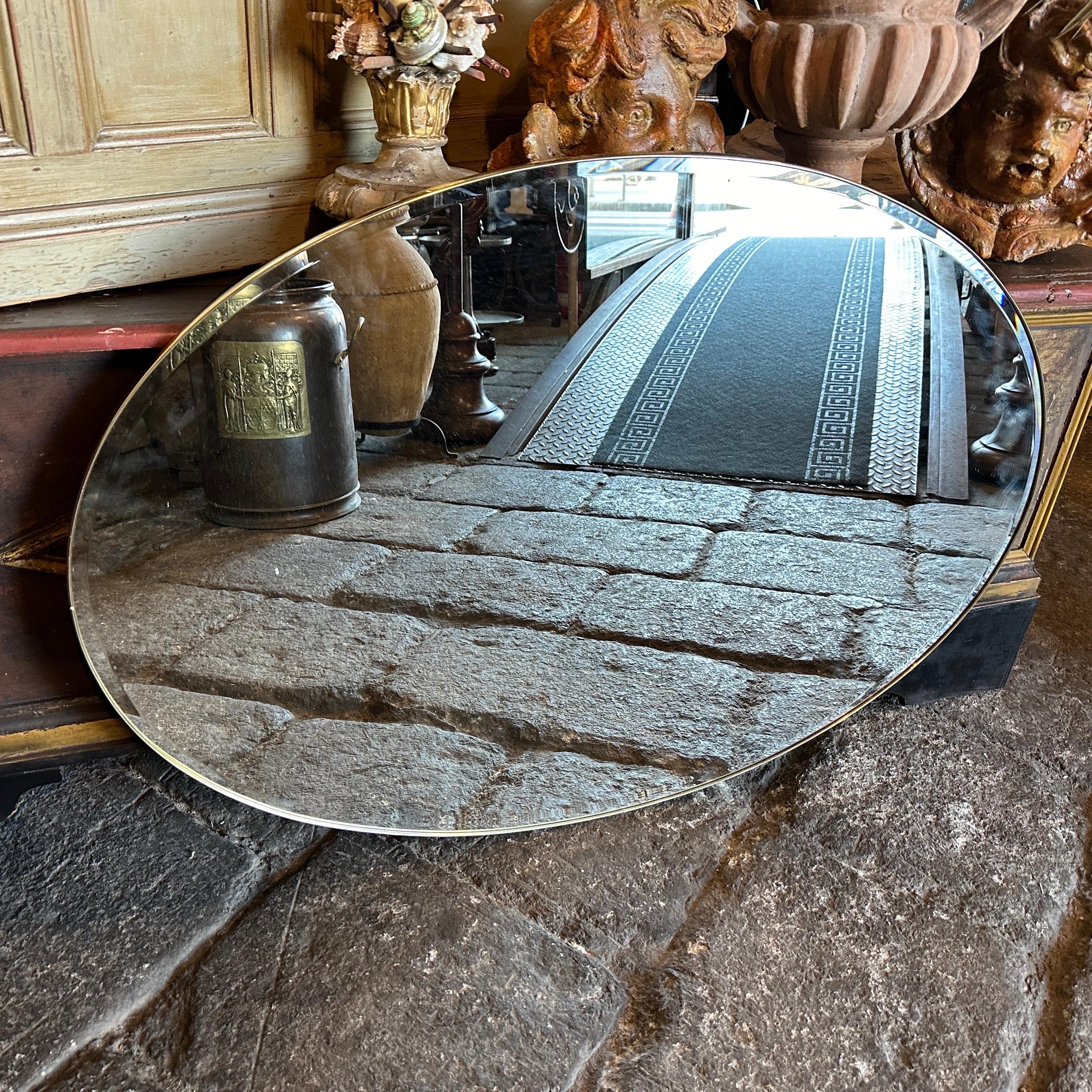 Miroir mural ovale en laiton massif conçu et fabriqué en Italie dans les années 50, le laiton est en patine d'origine et est en très bon état dans l'ensemble, le verre du miroir est celui d'origine. Les années 1960 ont été une période de grande