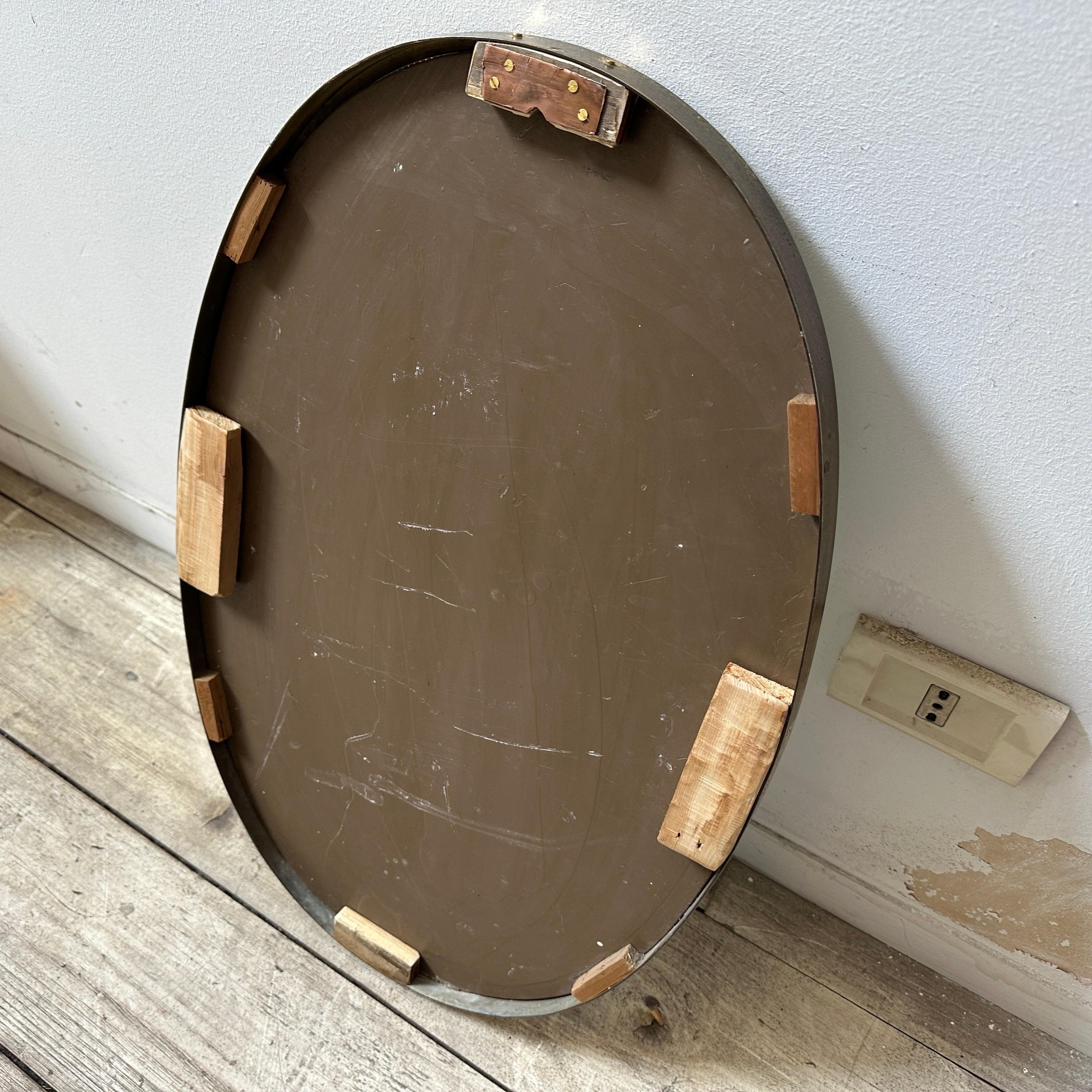 A solid brass oval wall mirror designed and manufactured in Italy in the Fifties, brass it's in original patina and has signs of use and age, mirror glass is the original one. The 1950s was a period of great creativity and innovation in the world of