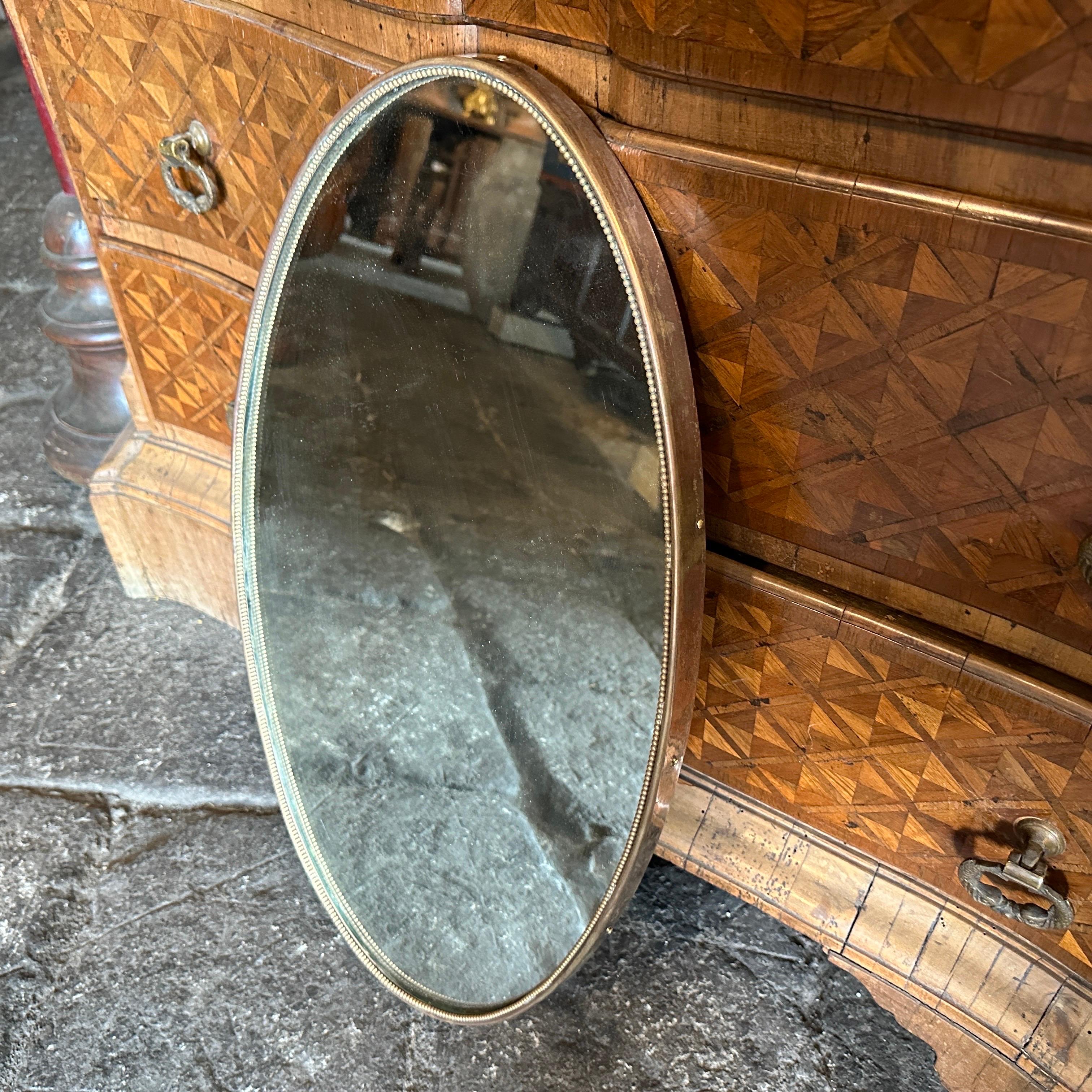 A solid brass oval wall mirror designed and manufactured in Italy in the Fifties, brass it's in original patina and has signs of use and age, mirror glass is the original one. The 1950s was a period of great creativity and innovation in the world of