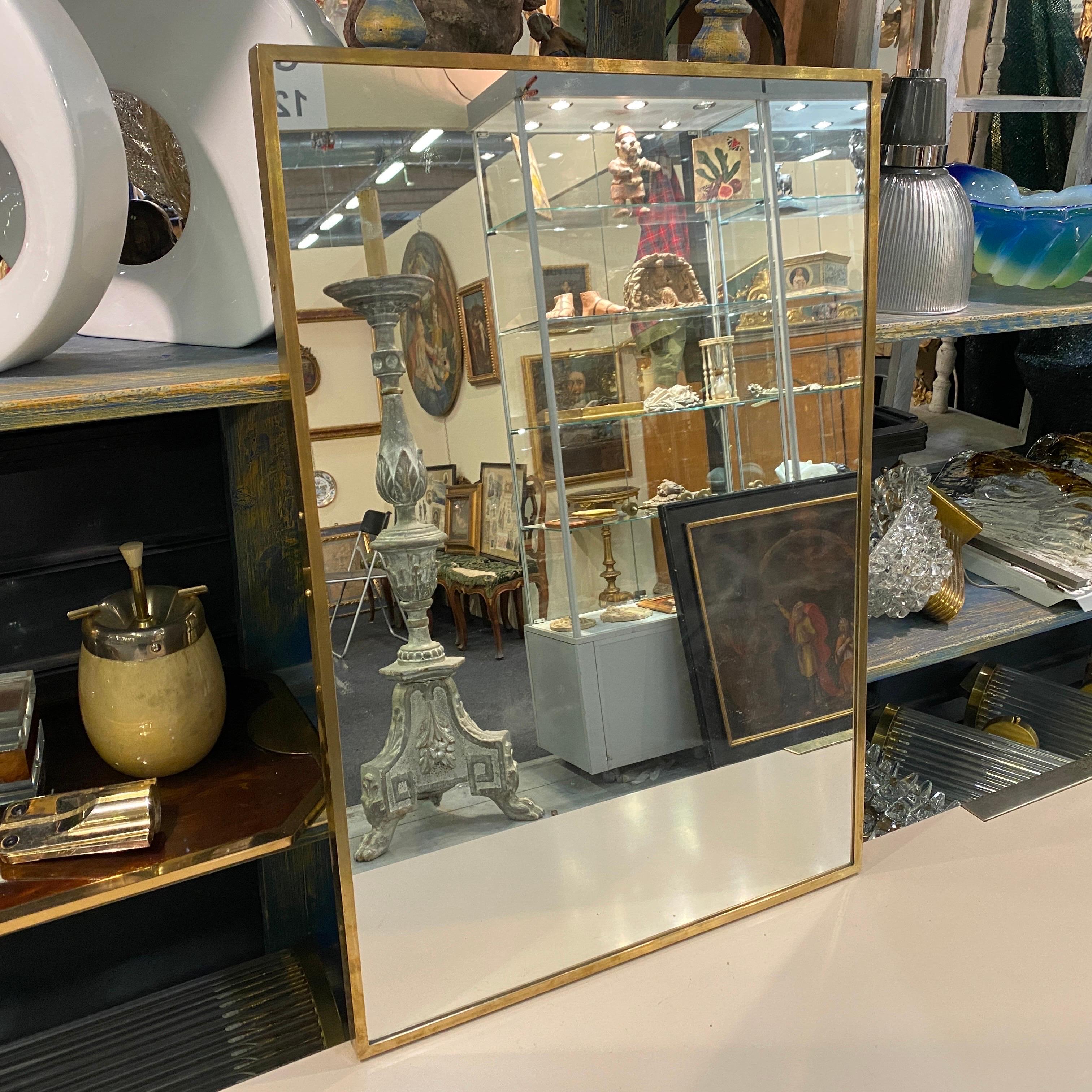 A brass rectangular wall mirror designed and manufactured in Italy in the early Sixties after the Brass mirrors production designed by Giò Ponti. Brass it's in original patina and gives it a vibrant Mid-Century Modern look.