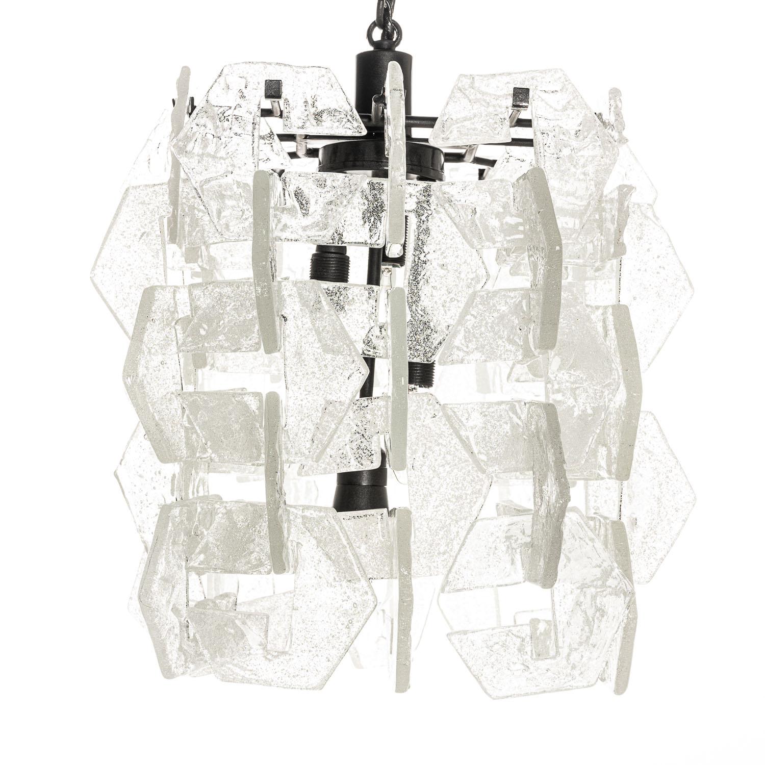 Cette pièce est l'œuvre du designer Carlo Nason. Les 60 pièces texturées qui entourent les quatre ampoules sont uniques et élégantes dans leur forme. Lorsqu'il est éclairé, il diffuse magnifiquement la lumière tout en soulignant le soin et